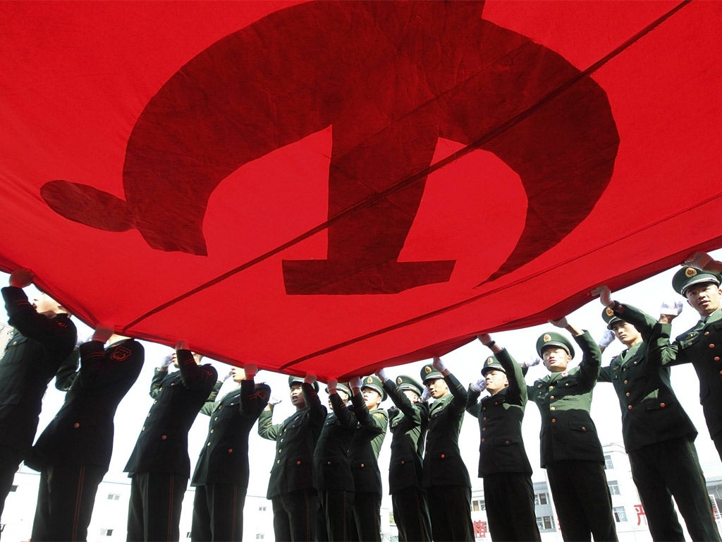 Soldiers in Beijing hold up the Communist Party flag