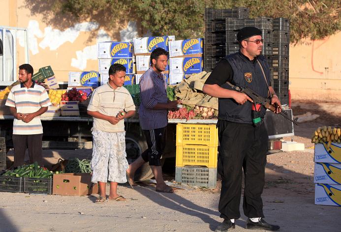 A pro-government Libyan fighter holds his gun as people shop at a market in the city of Bani Walid
