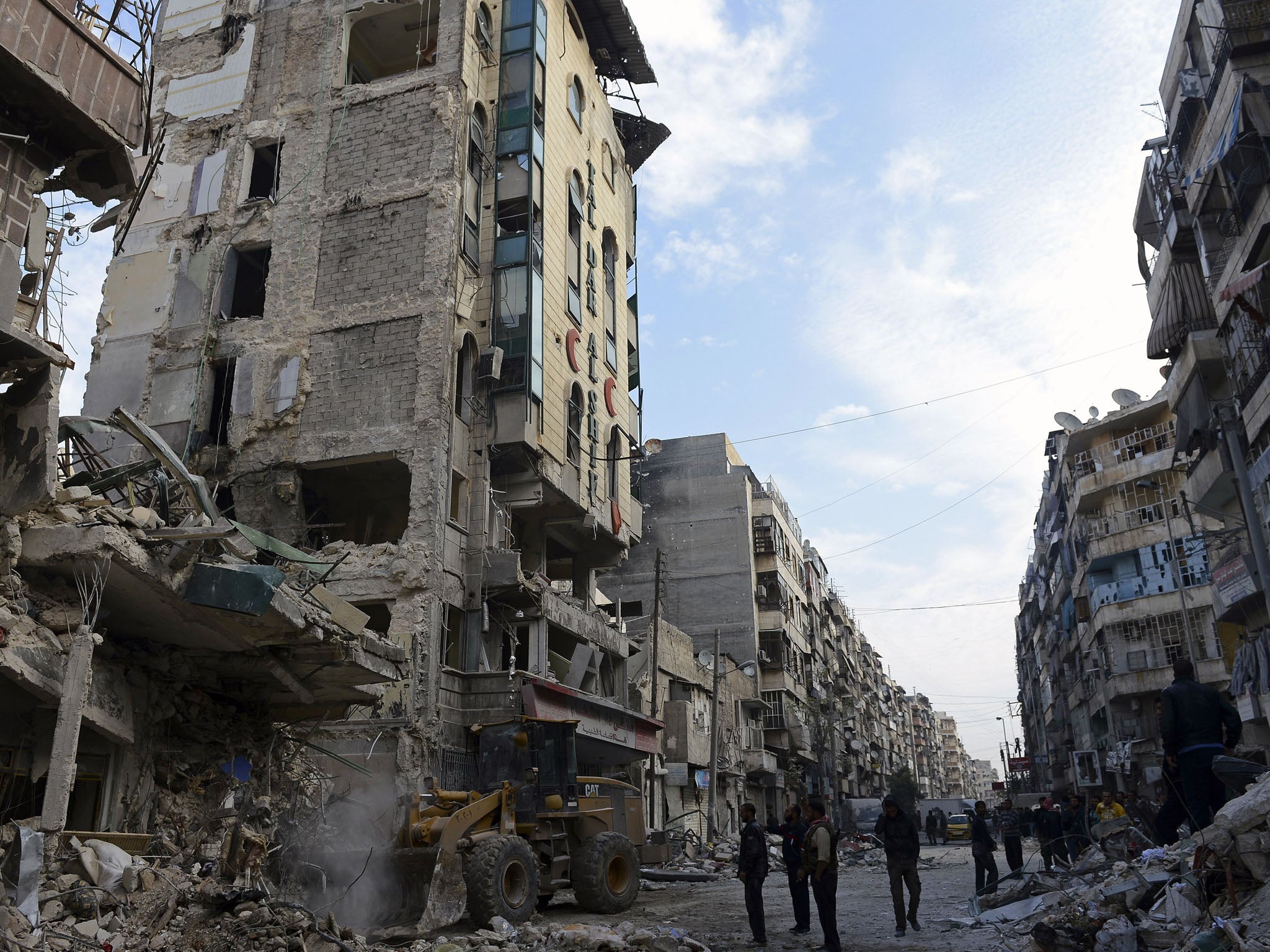 Syrian rebels and bystanders watch a bulldozer clean the debris outside Dar Al-Shifa hospital in Aleppo, northern Syria.