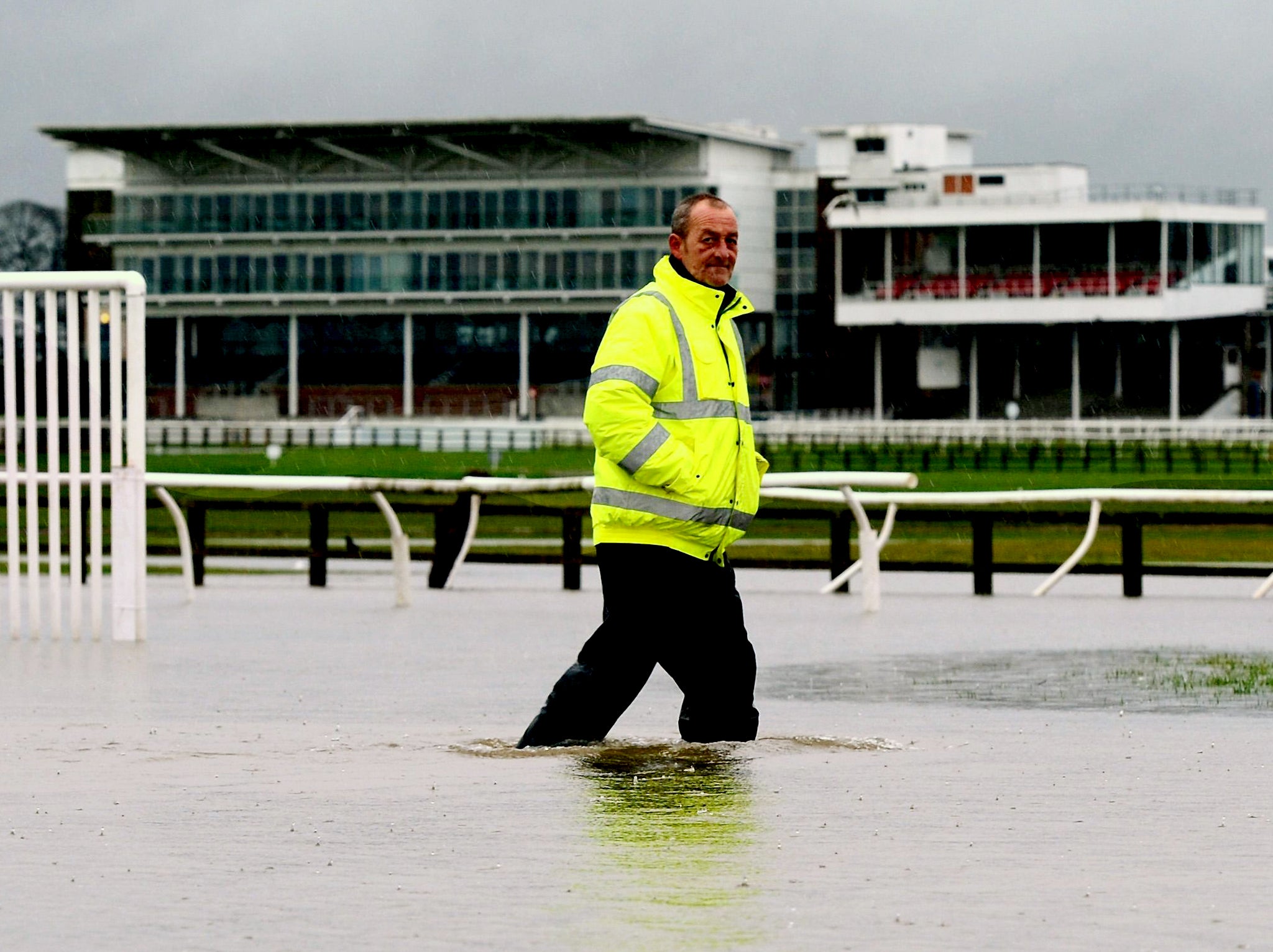 Head Groundsman Ian Ward wades through floodwater on the track following torrential rain at Wetherby Racecourse