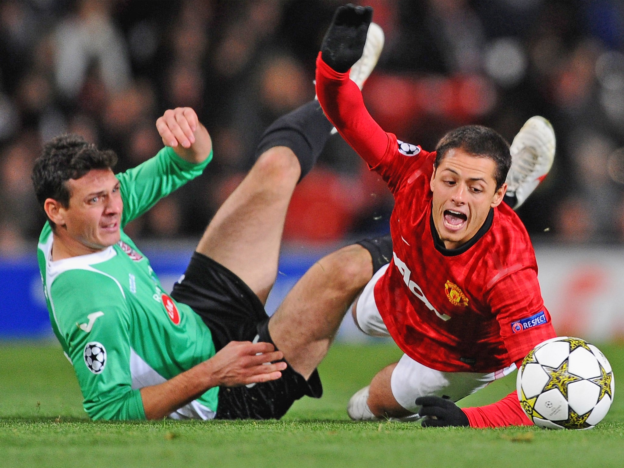 Manchester United’s Javier Hernandez falls under a challenge from Cluj’s Ionut Rada