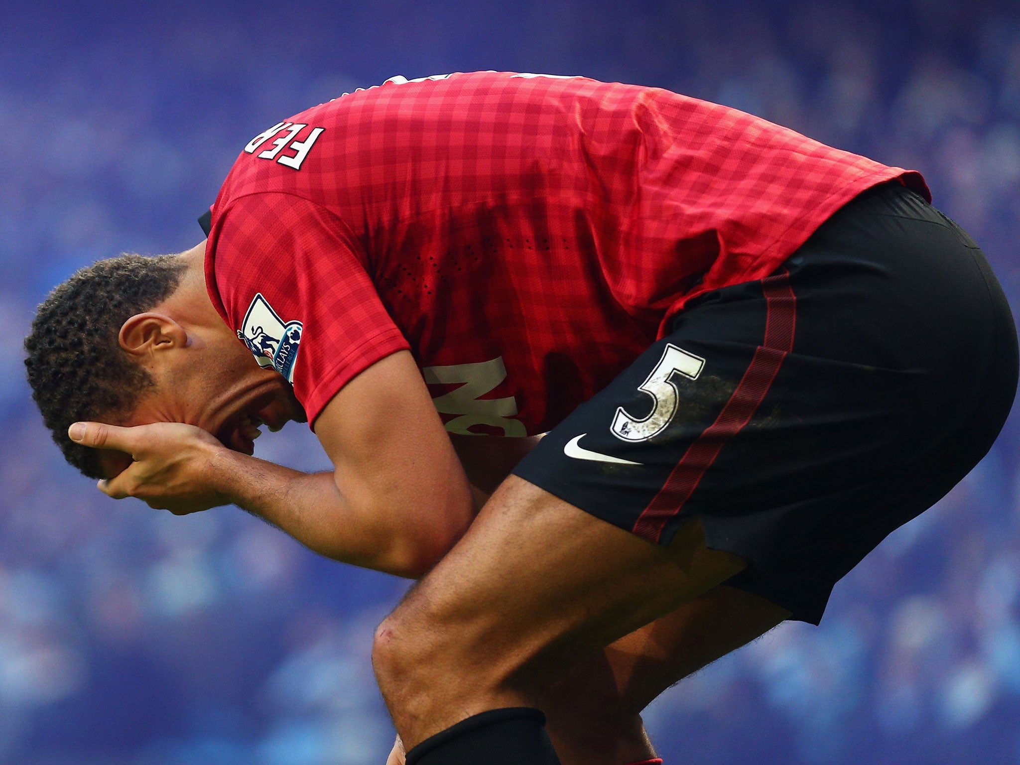 Rio Ferdinand of Manchester United reacts after being struck by an object thrown from the crowd