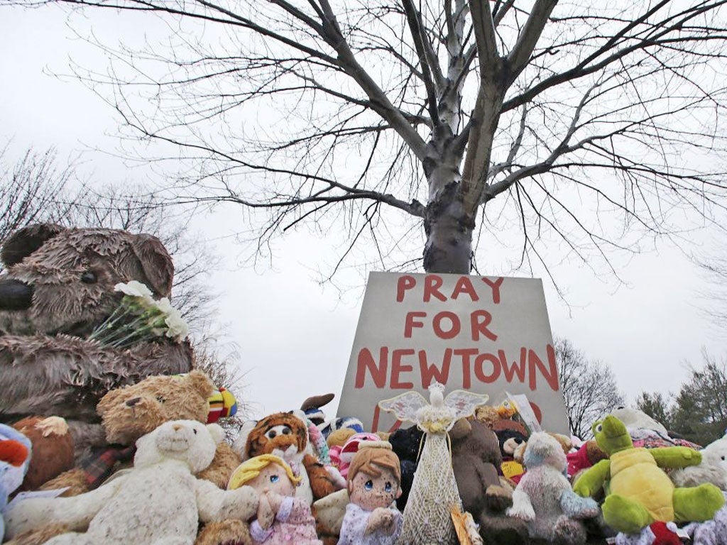 Stuffed animals and a sign calling for prayer rest at the base of a tree near the Newtown Village Cemetery in Newtown