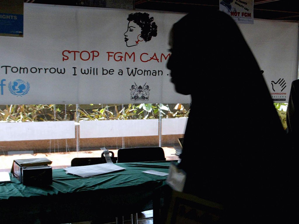 A young woman walks past a campaign banner against female genital mutilation [FGM] at the venue of an International conference, 16 September 2004 in Nairobi.