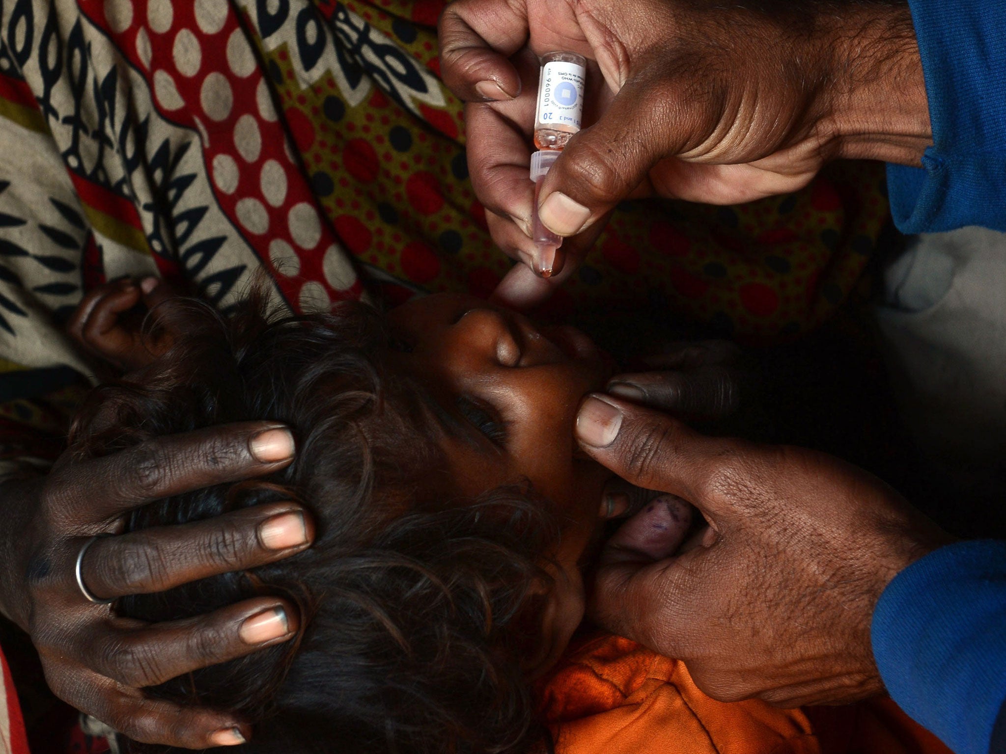 A Pakistani health worker gives polio vaccine drops to a young child last week