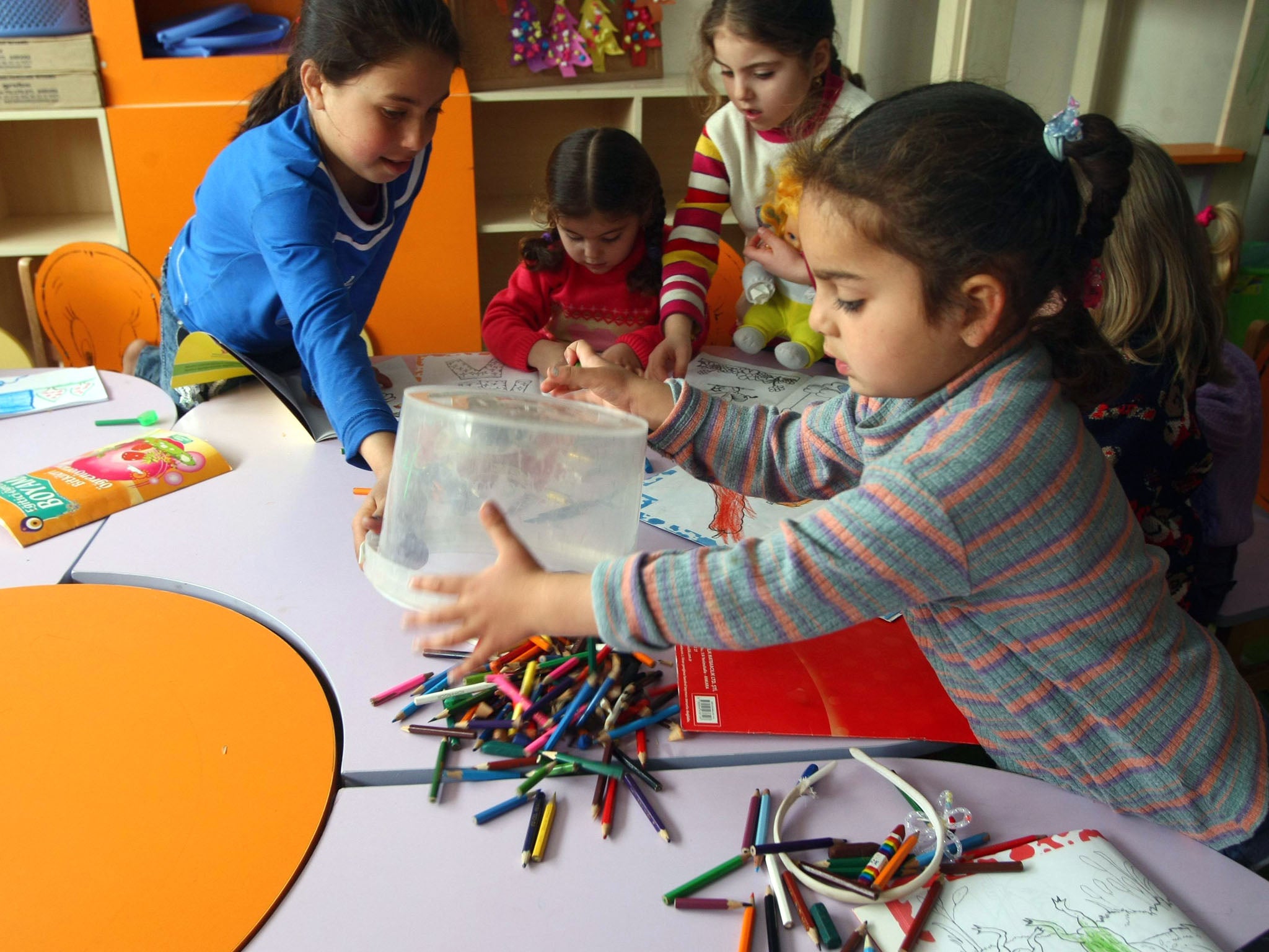 Syrian refugee children colour-in pages during a class at the refugee camp in Yayladagi