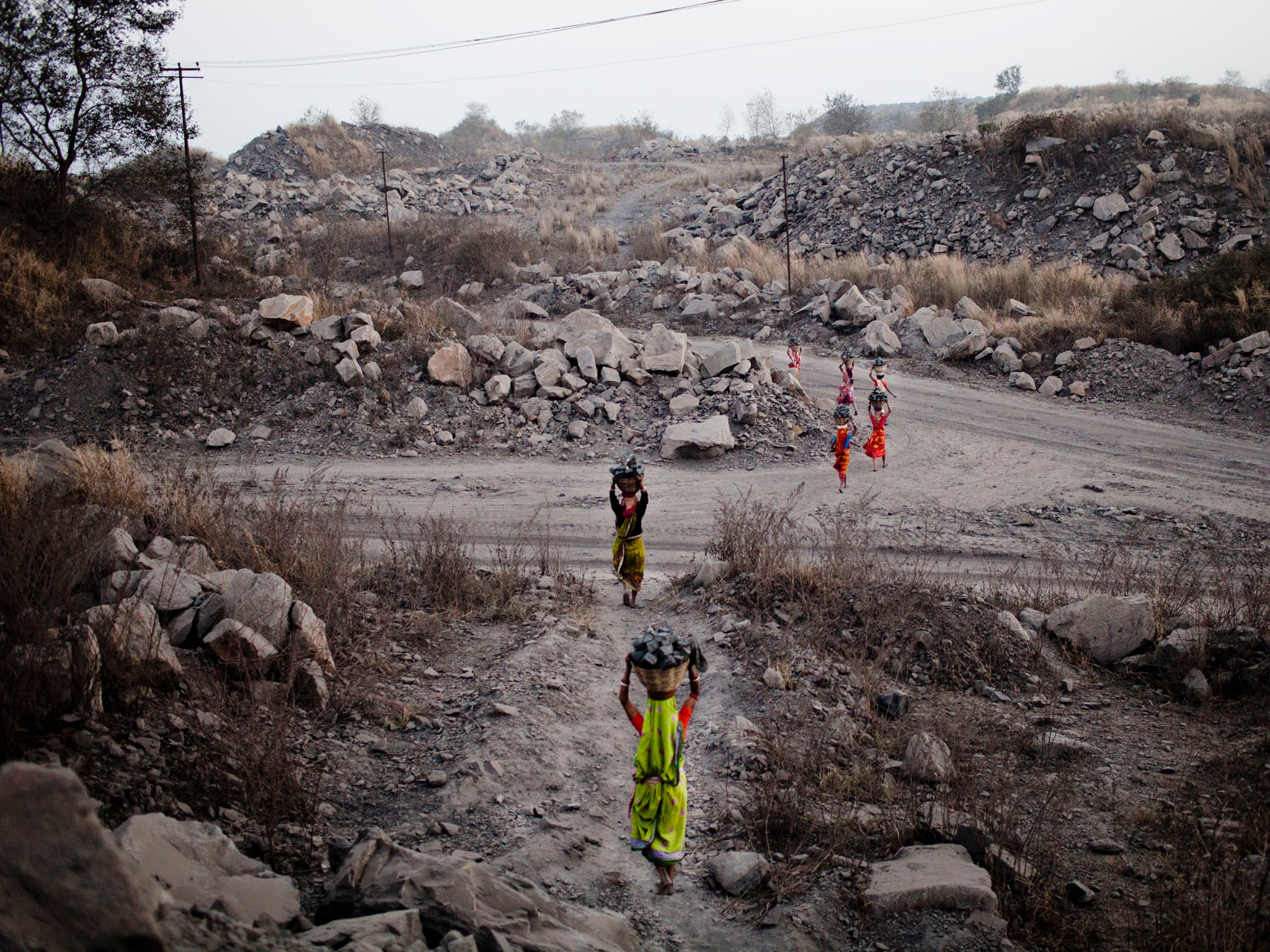 Women carry baskets of coal back to their village for sale, after having scavenged the coal illegally from an open-cast coal mine in the village of Jina Gora