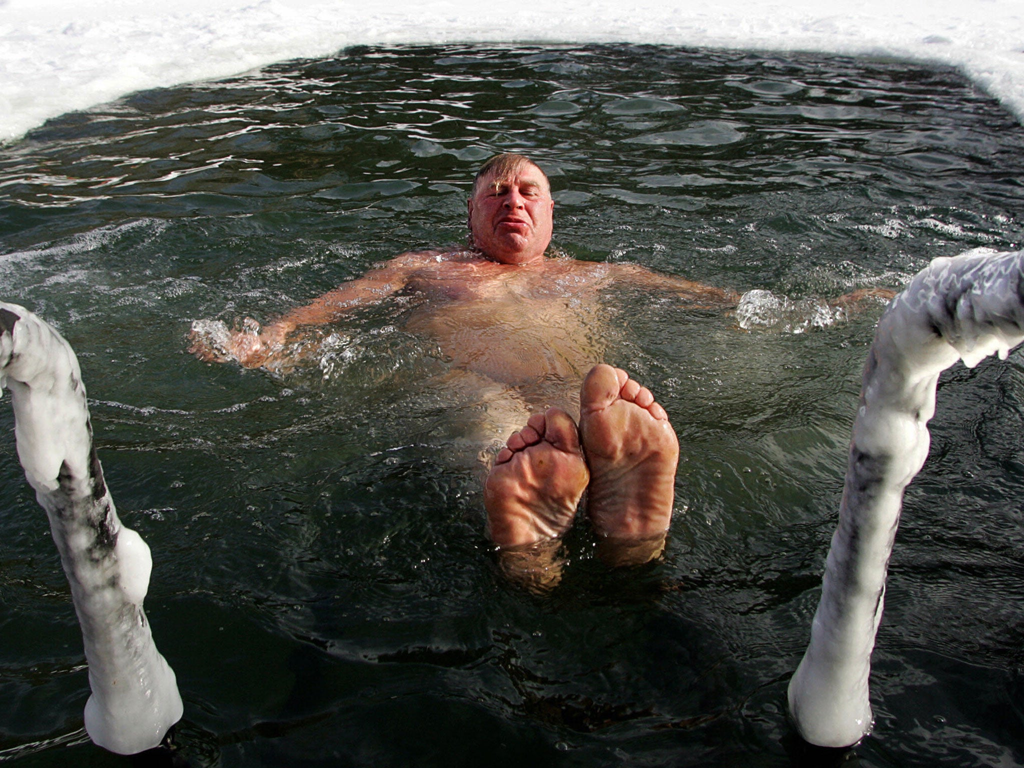 A man enjoys swimming in icy water of a frozen park pond in Moscow, 24 February 2007.