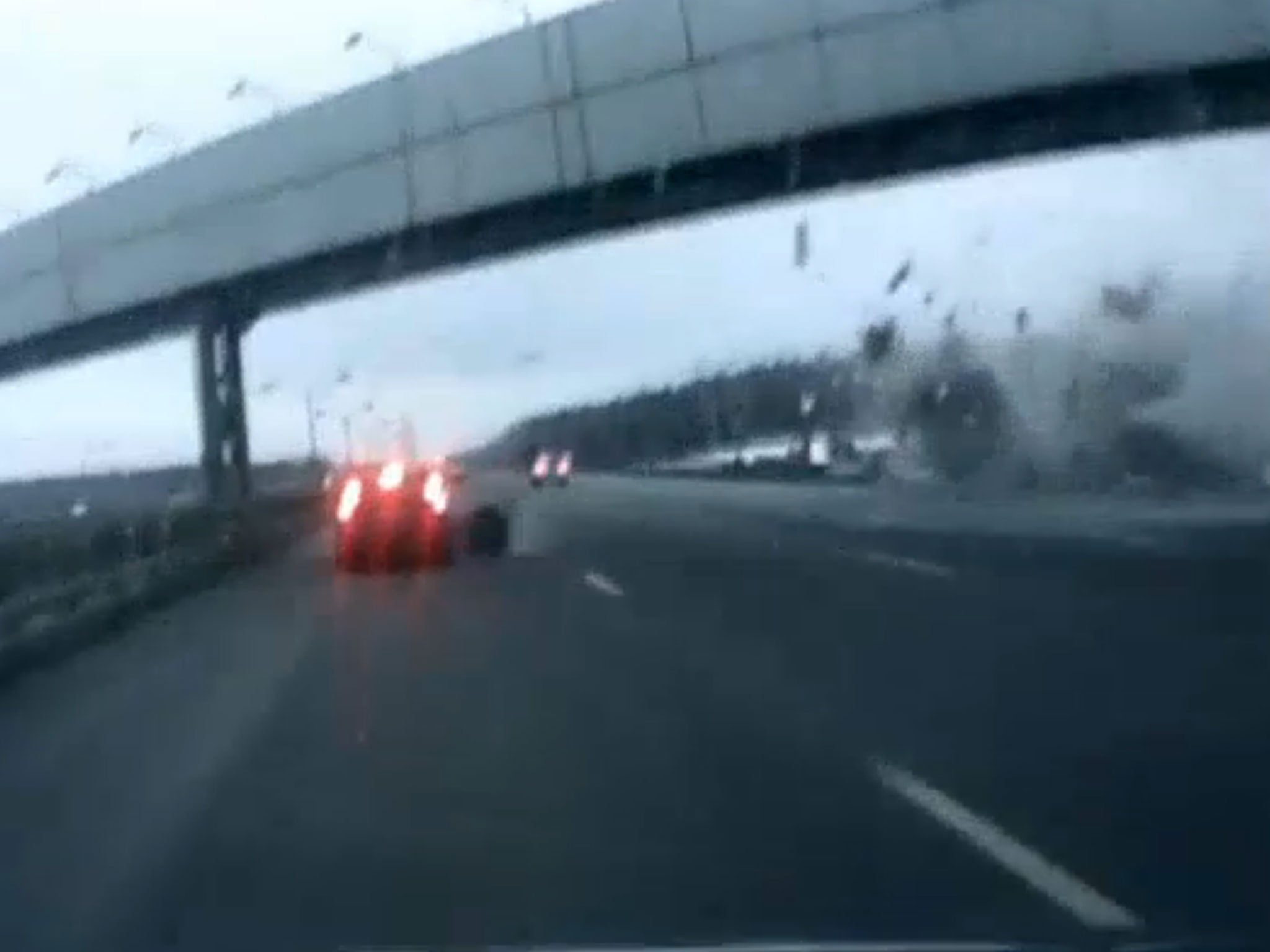 The camera catches the moment the plane hits a Moscow motorway, showing a wheel from the plane slamming into the side of one vehicle as debris is strewn across the road.