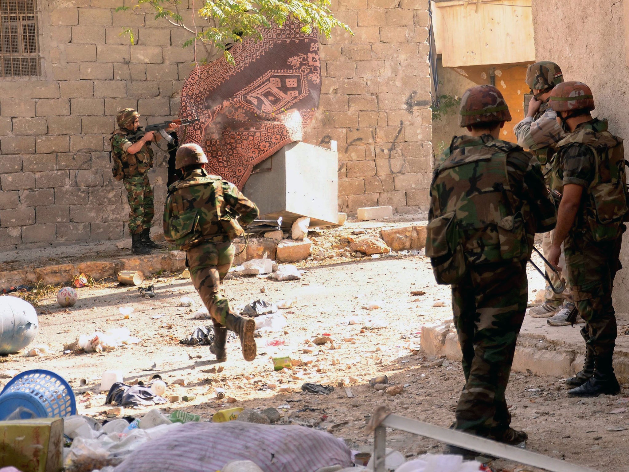 A Syrian army soldier runs across the street as others open fire during clashes with opposition fighters in the Tal al-Zarazi neighbourhood of the northern Syrian city of Aleppo on November 13, 2012.