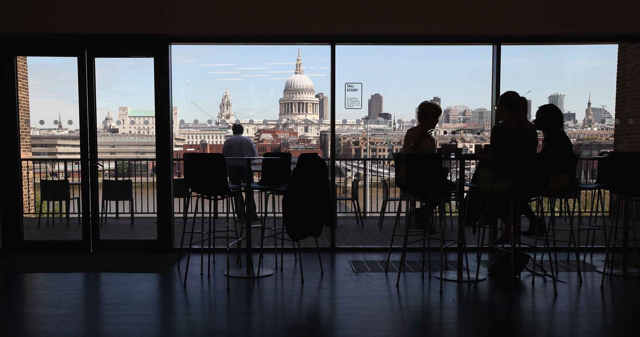 Members of the public sit in a cafe on an upper floor of the Tate Modern gallery overlooking the River Thames and St Paul's Cathedral