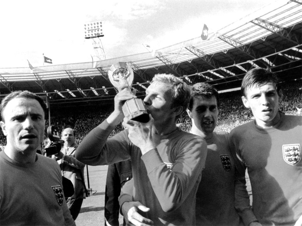 George Cohen (left) looks on as England captain Bobby Moore kisses the Jules Rimet trophy in 1966