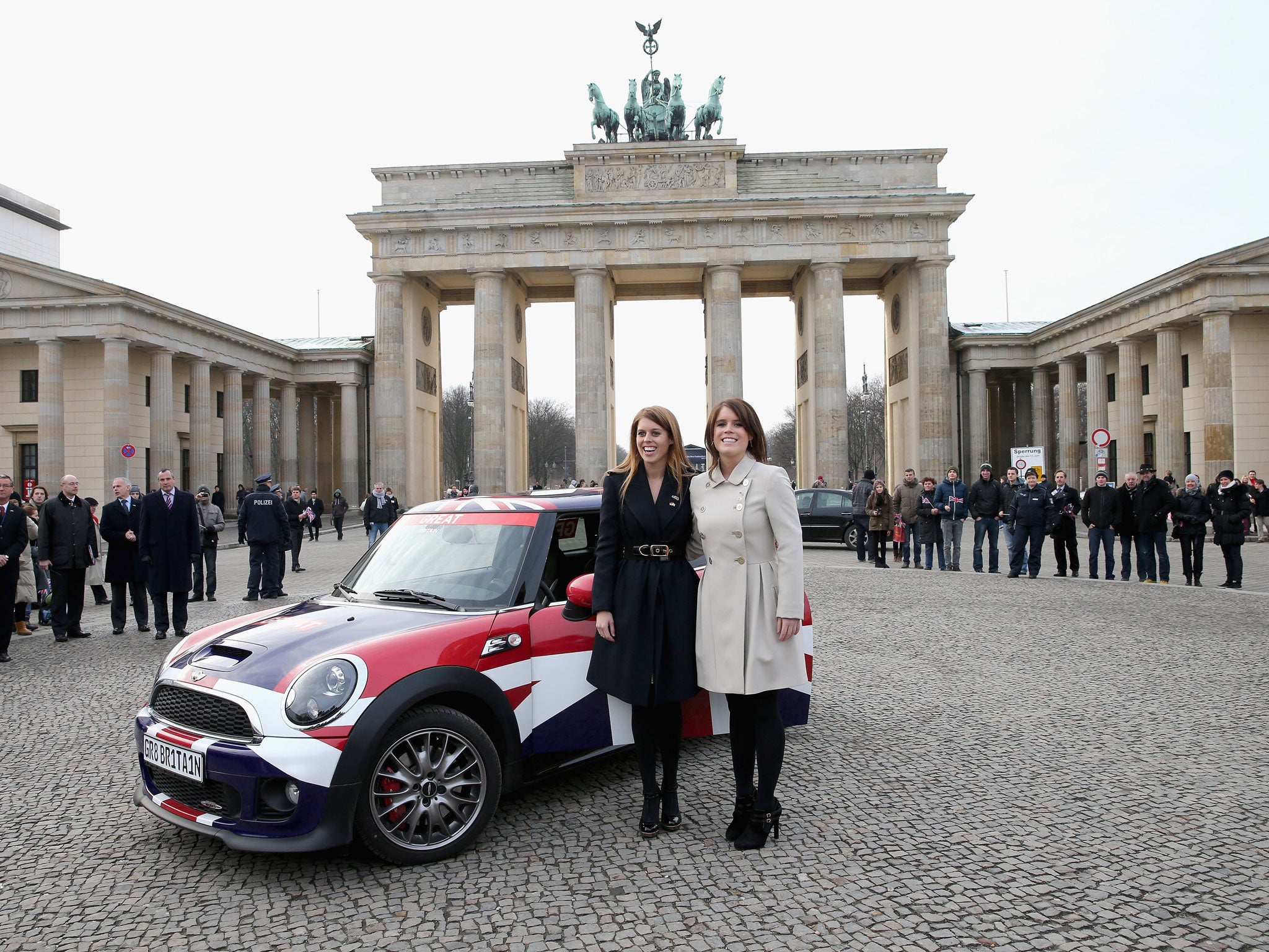 Princess Beatrice and Princess Eugenie pose next to a Mini in front of Brandenburg Gate as they promote the GREAT initiative