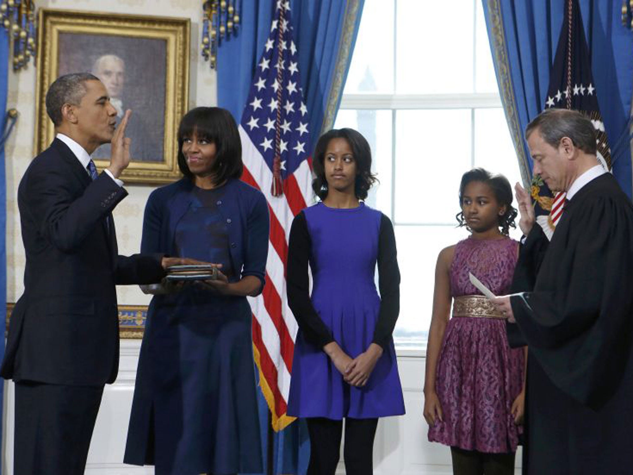 Obama is sworn in by Chief Justice John Roberts, right, in the White House as his family look on