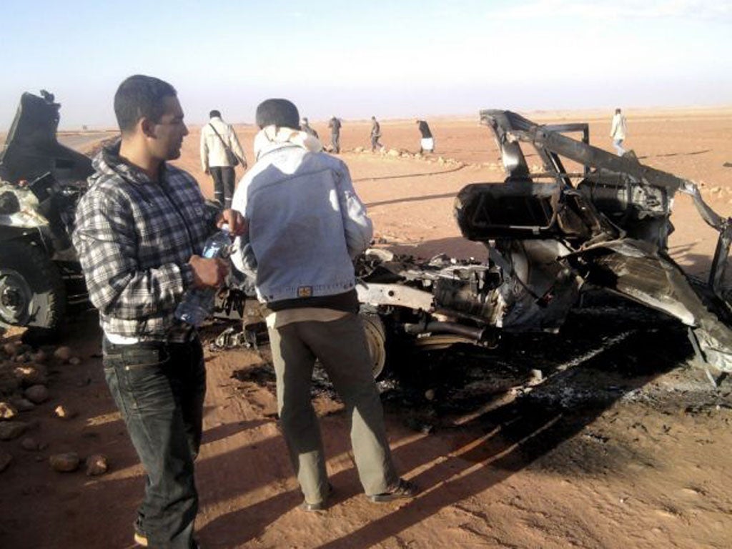 Men look at the wreckage of a vehicle near Ain Amenas, Algeria