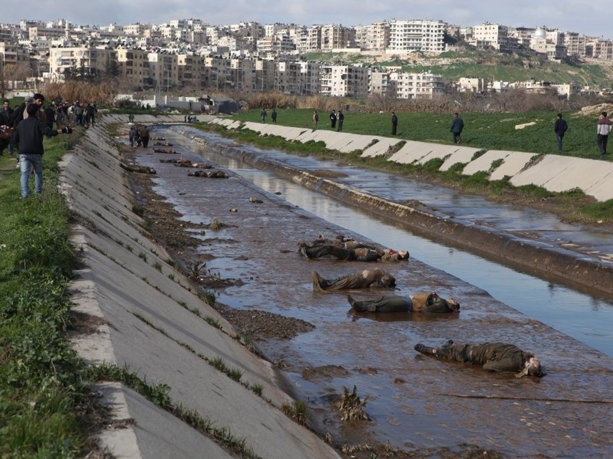 Locals gather at the banks of a small canal coming from a government-controlled suburb of Aleppo to view dozens of bodies of people