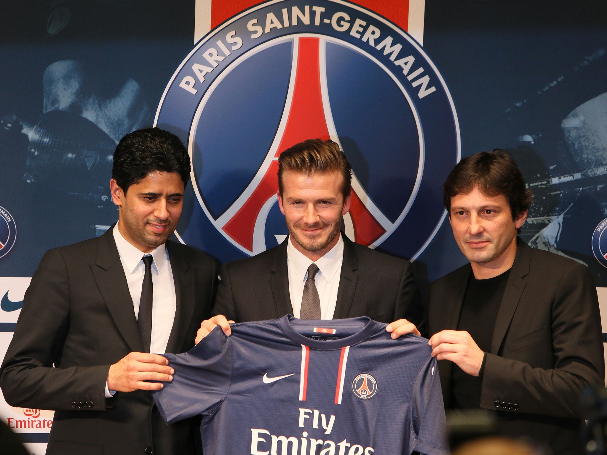 David Beckham (C) poses presenting his new shirt flanked by PSG Qatari president Nasser Al-Khelaifi (L) and PSG sports director Leonardo