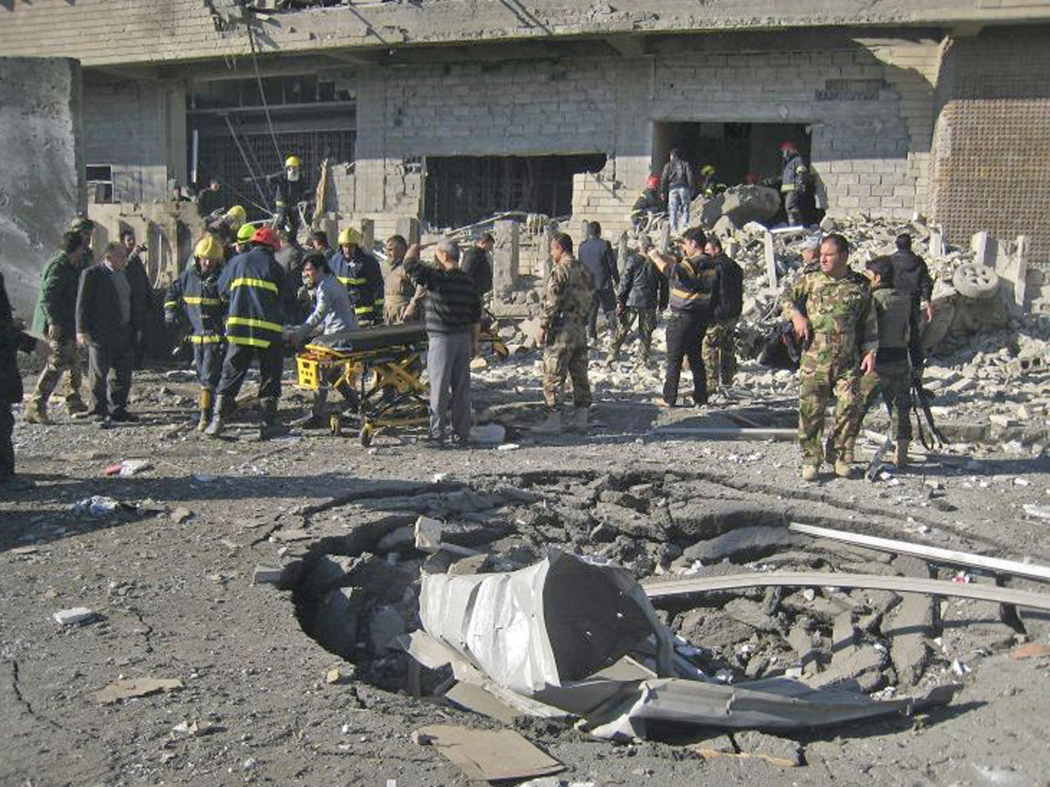 Iraqi civilians and security forces inspect a crater caused by a car bomb attack in Kirkuk, north of Baghdad, Iraq today. A suicide car bomber joined by other suicide attackers on foot assaulted a provincial police headquarters