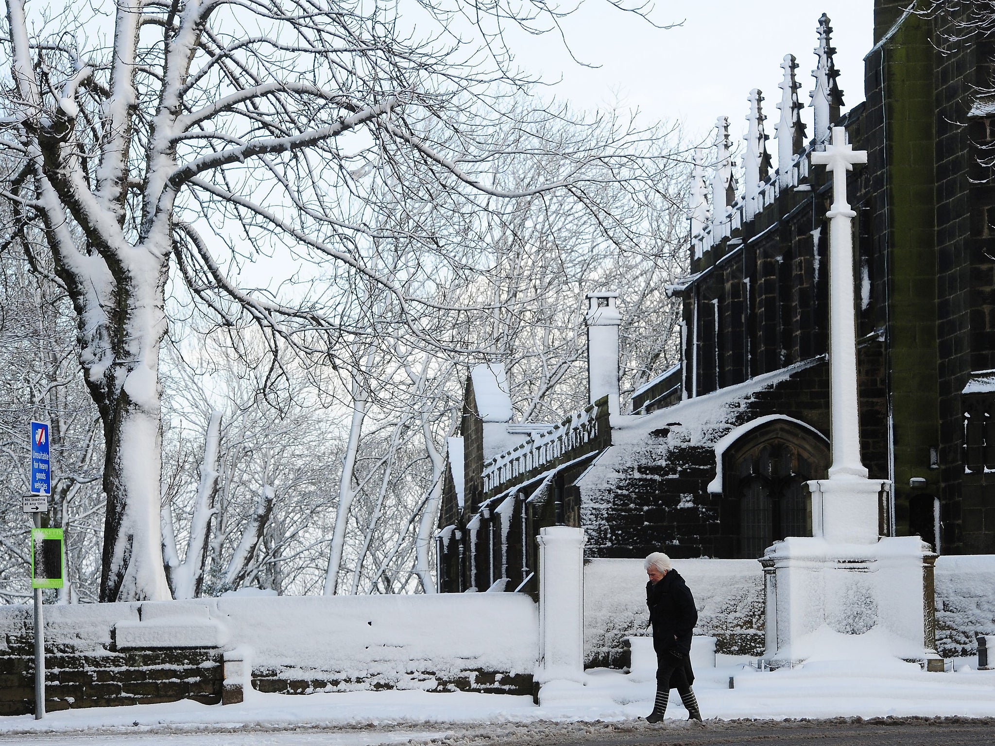 A woman makes her way past the St John the Baptist Church in Penistone, South Yorkshire, as parts of Britain brace for a return of snow and gales