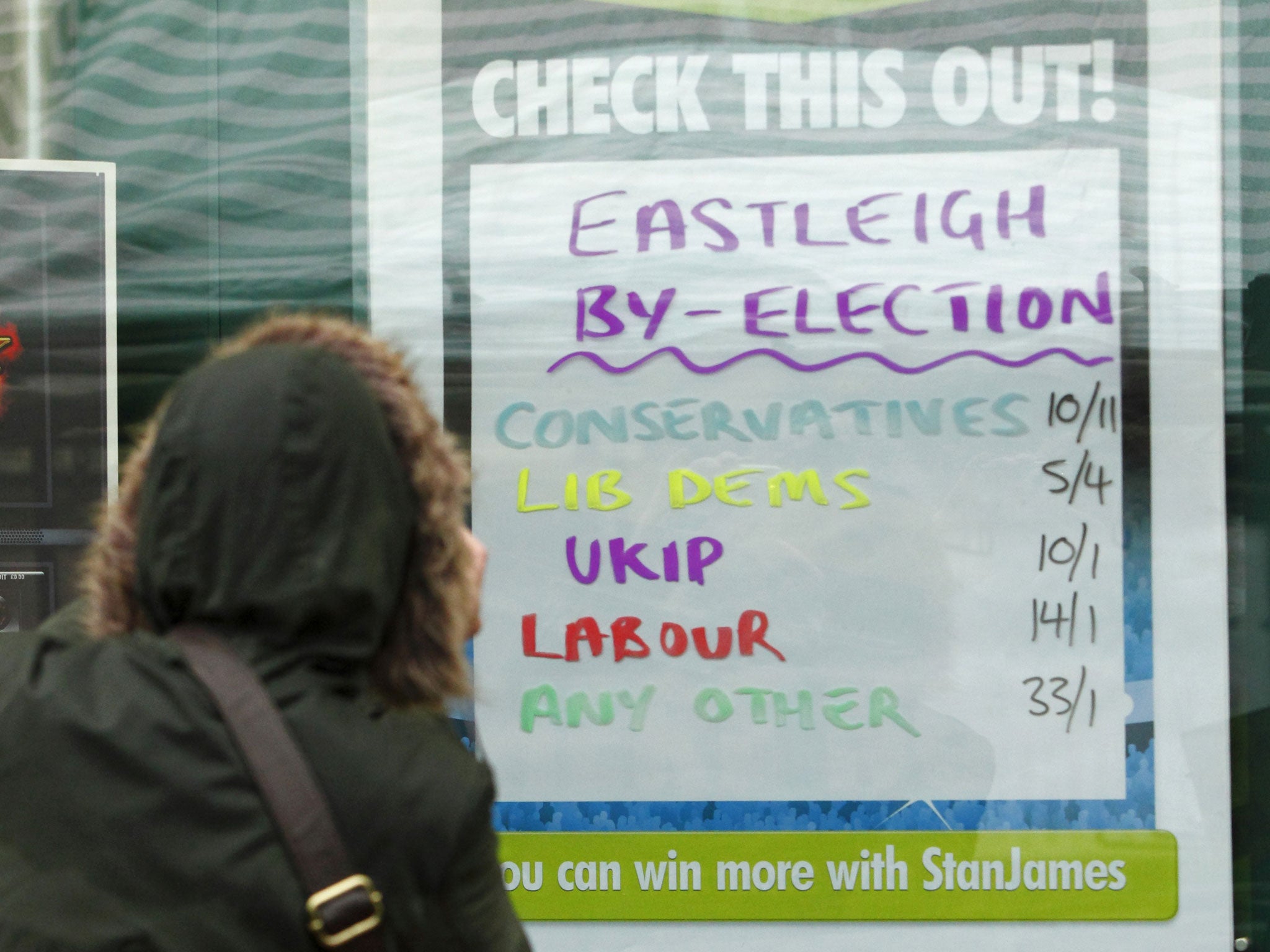 Place your bets: A woman checks the political parties’ odds in a bookmaker’s window in Eastleigh, Hampshire, yesterday