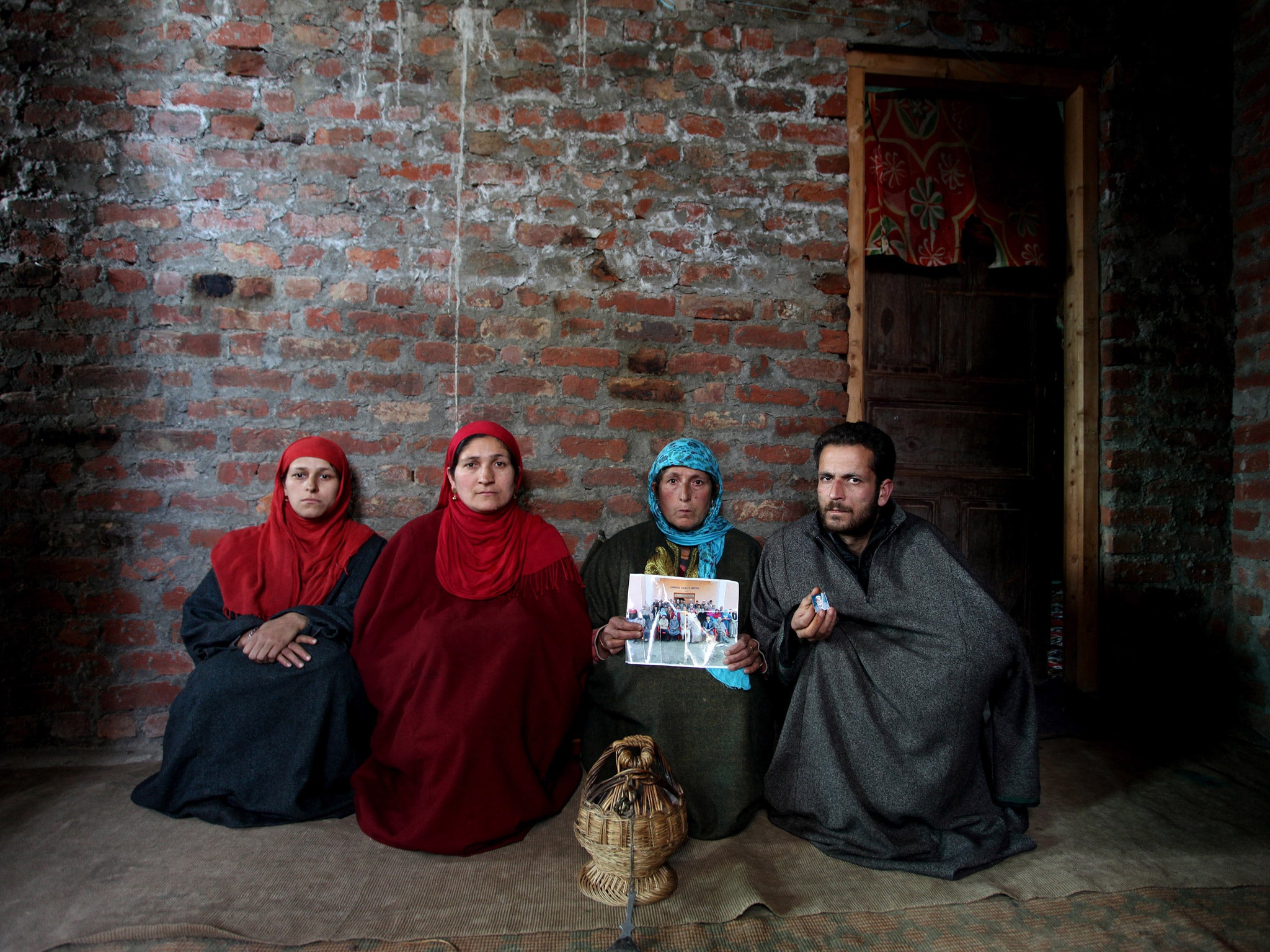 A Kashmiri Muslim family holds a picture of Habibullah Mir who was allegedly killed by an unidentified gunman