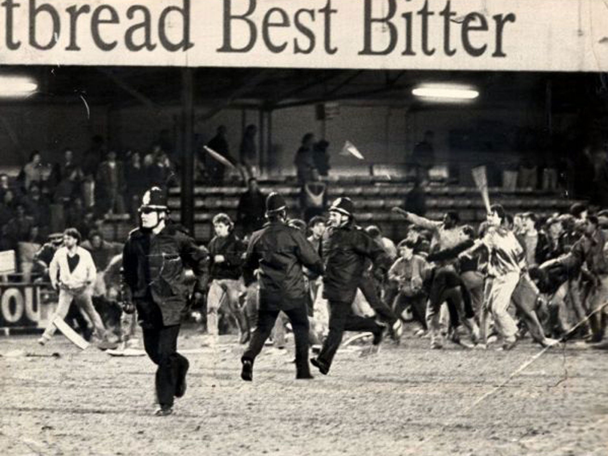 Millwall fans storm past police officers and on to the pitch at Kenilworth Road in 1985