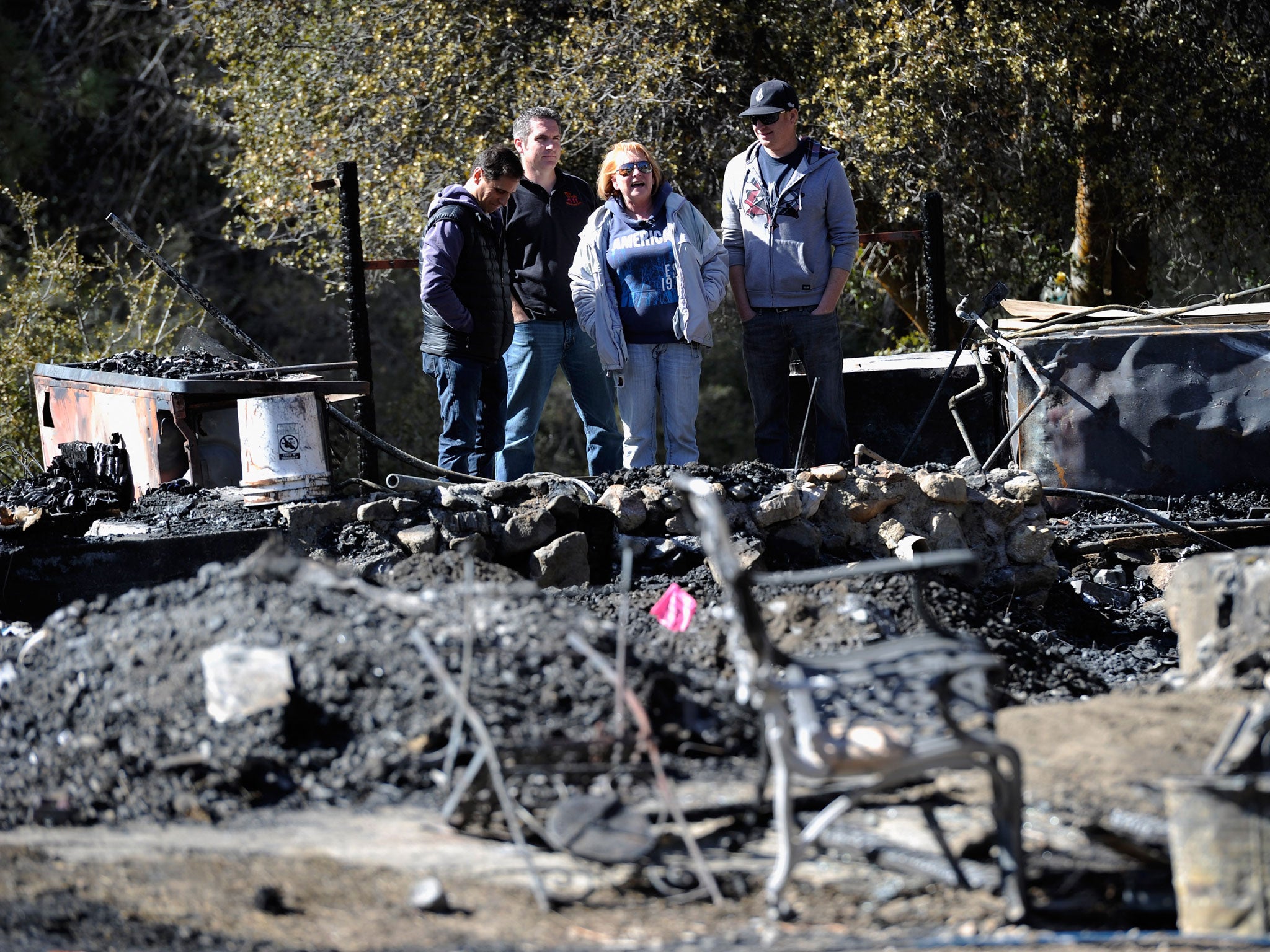 Candy Martin (centre) surveys the damage with family members and friends at her burned-out cabin where the remains of multiple murder suspect and former Los Angeles Police Department officer Christopher Dorner were found on Friday