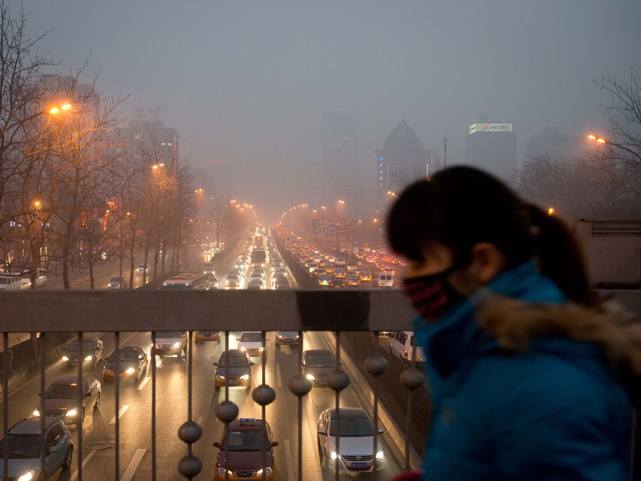 A woman wearing a mask walks over a road bridge in heavy pollution on January 28, 2013. The US embassy air quality index twitter feed recorded levels classed as 'hazardous', with a figure of 493 -- almost 20 times the World Health Organisation's safe limit.