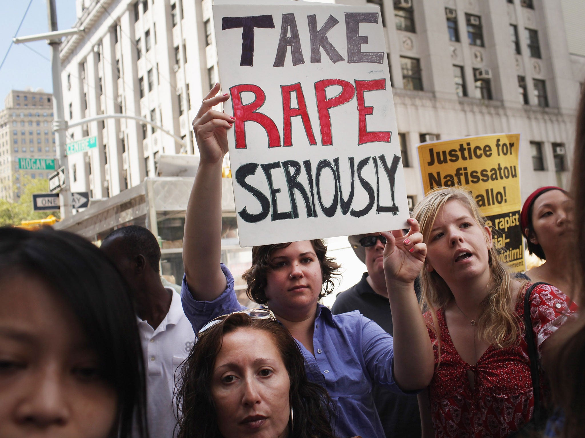 Protesters stand outside of a Manhattan court as former IMF director Dominique Strauss-Kahn exits the court on August 23, 2011 in New York City.