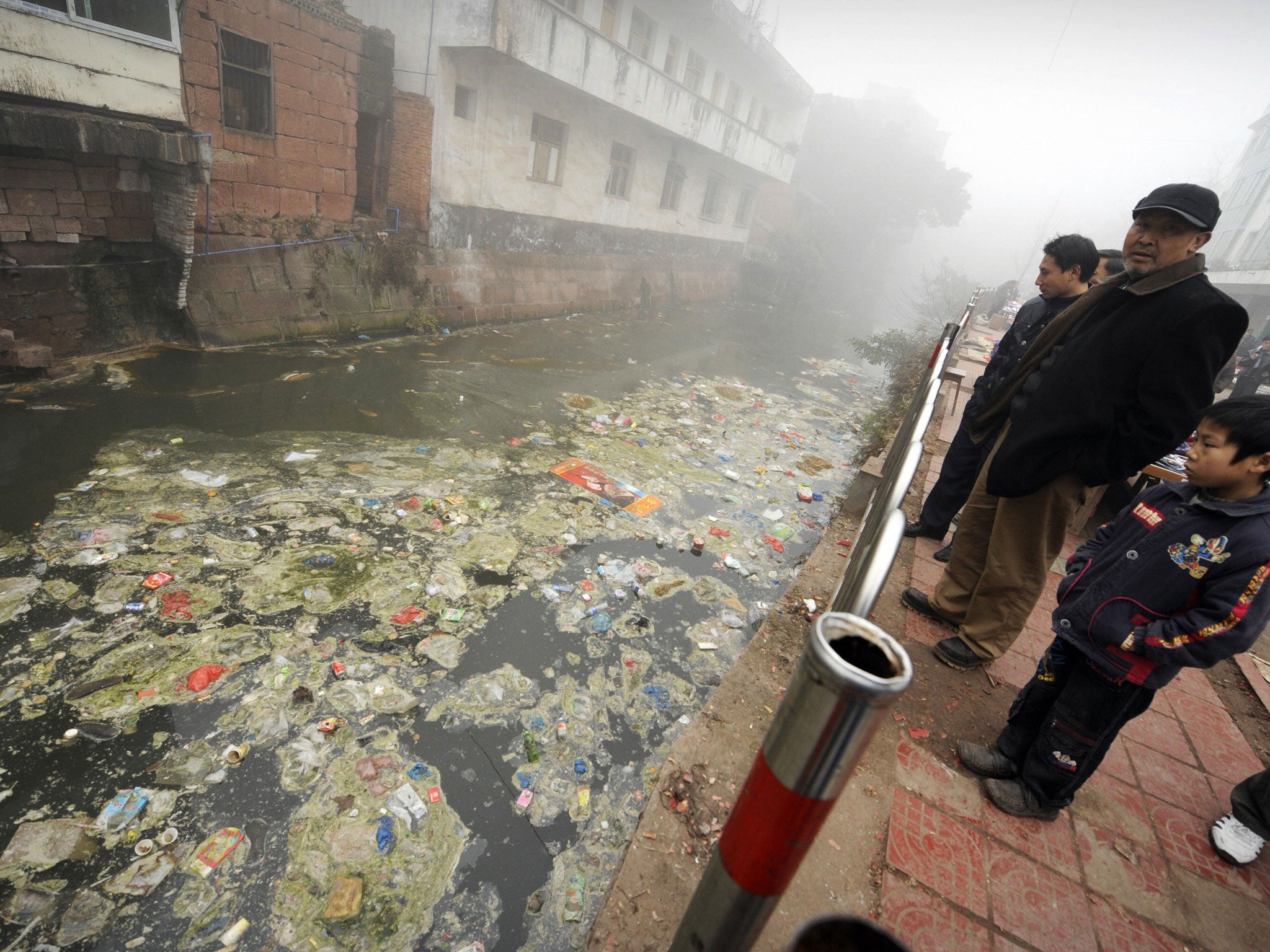 Residents look at a heavily polluted river in the town of Zhugao in China's southwest Sichuan province