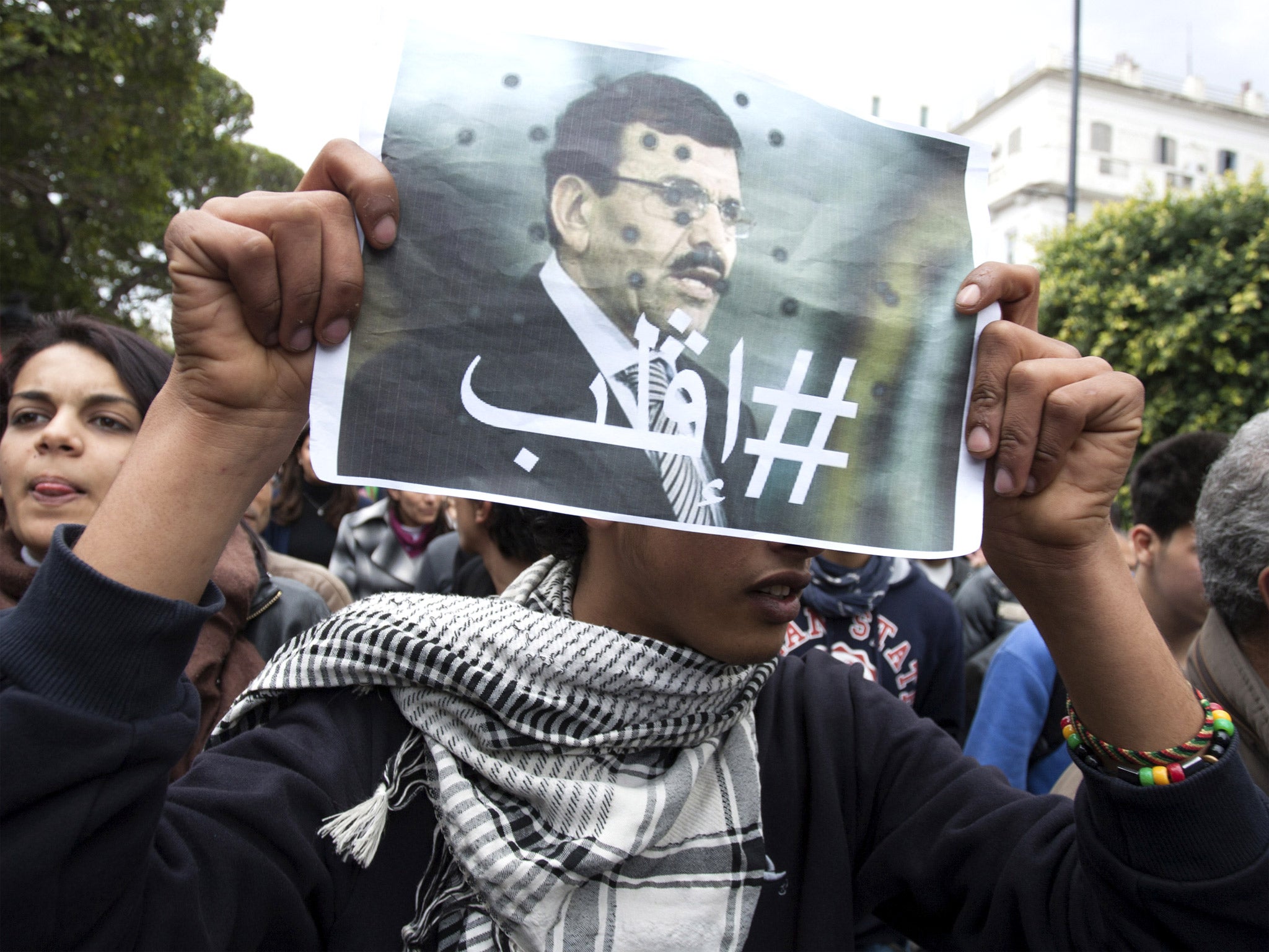 Protesters hold aloft posters of Chokri Belaid who was shot dead outside his home