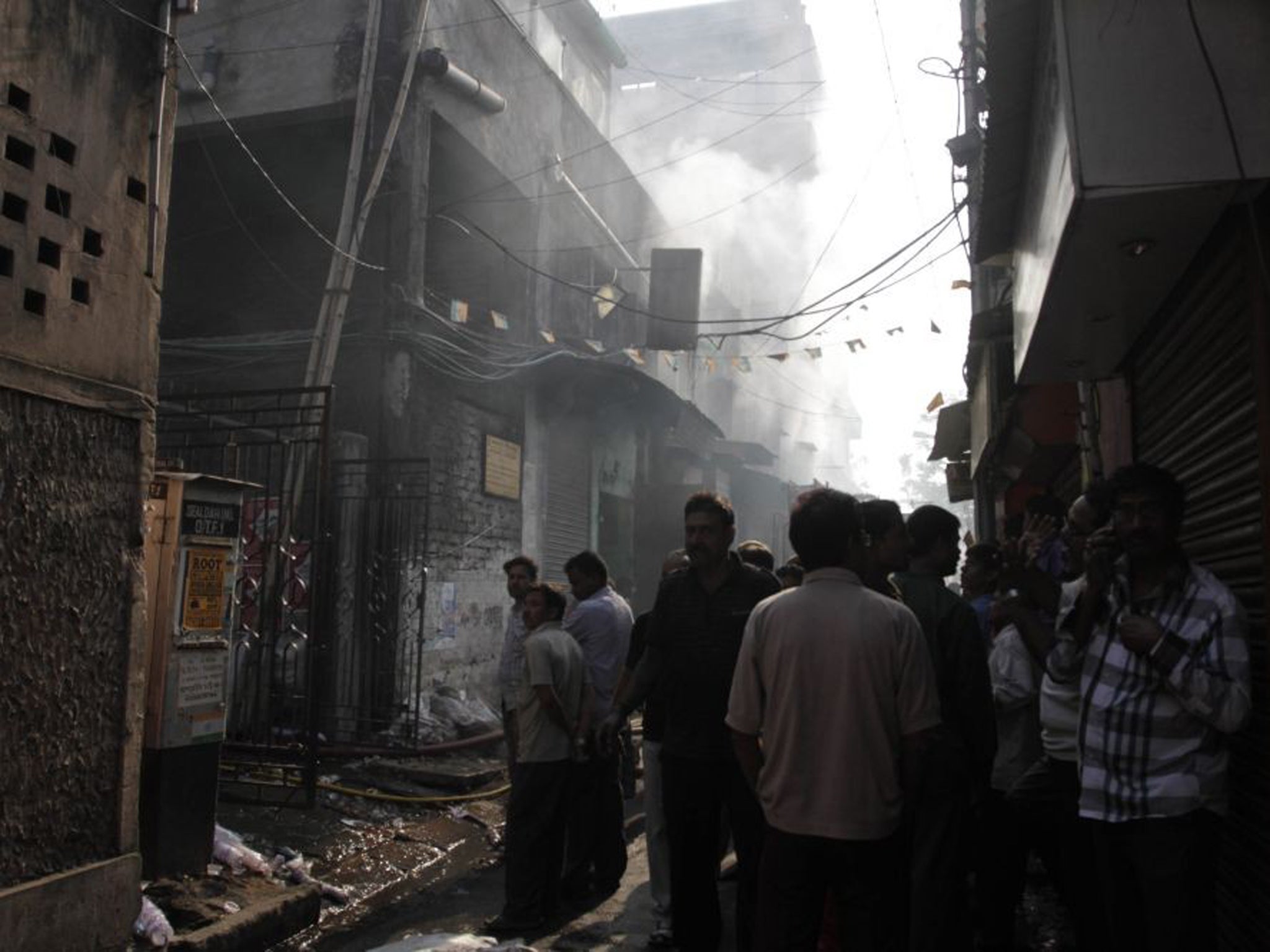 Residents and onlookers wait outside the smoldering buildings where the fire broke out