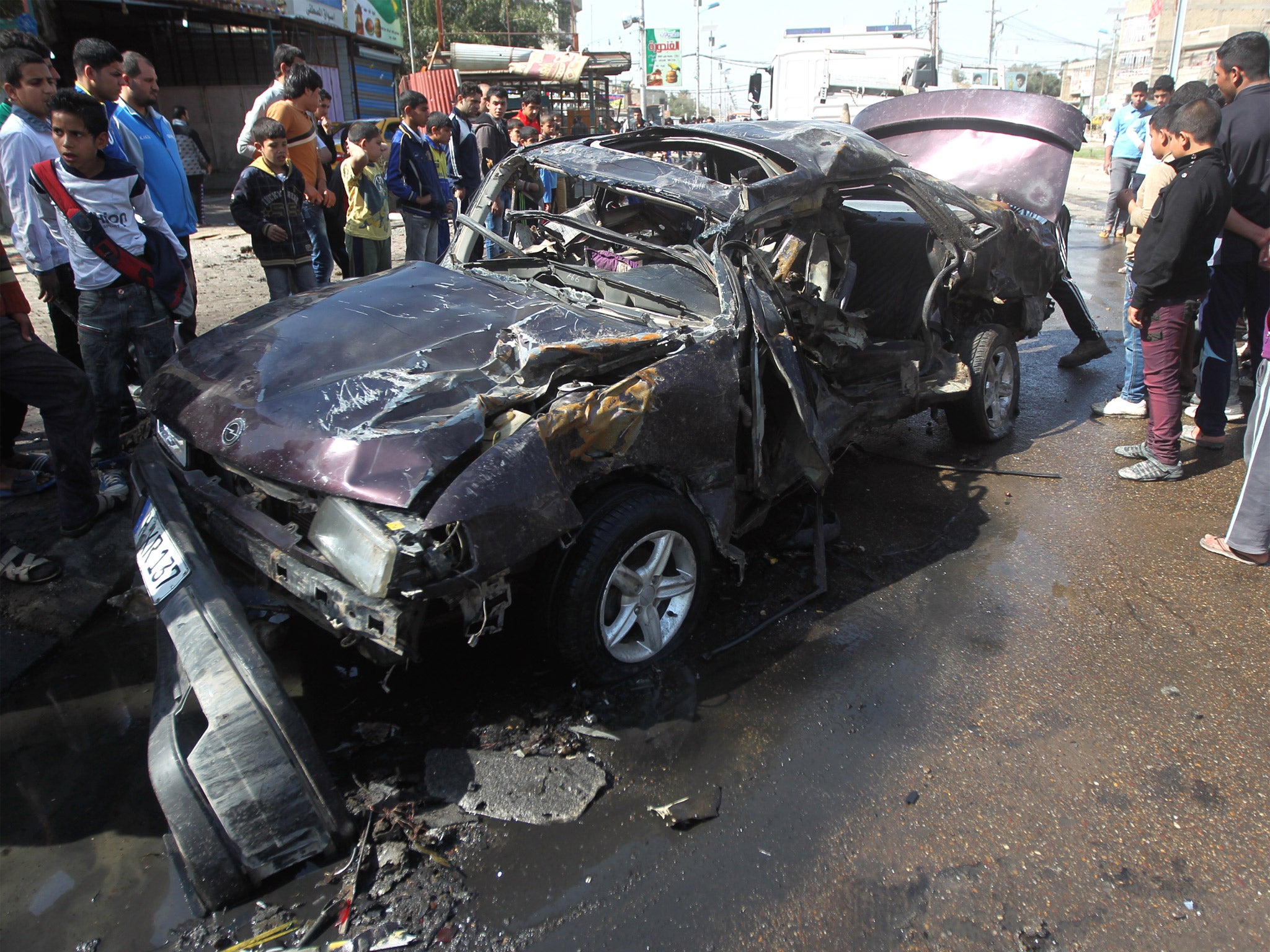 Iraqis inspect the site of a car bomb attack in Baghdad's impoverished district of Sadr City last month