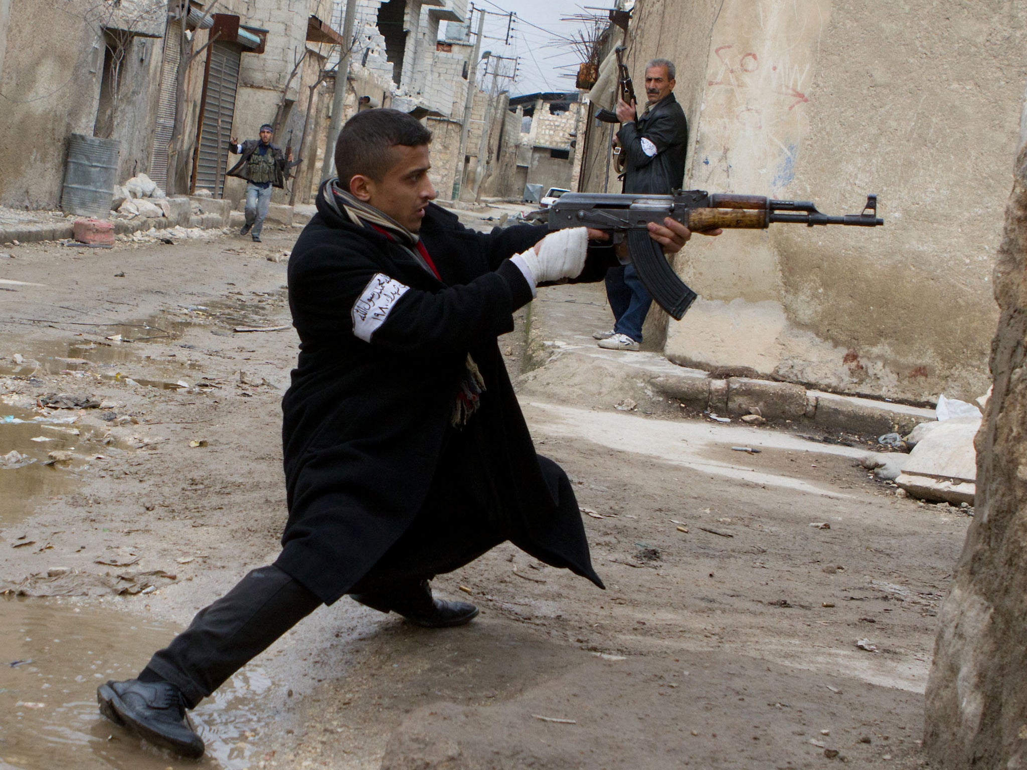 A Syrian rebel aims his weapon during clashes with government forces in the streets near Aleppo international airport in northern Syria on 4 March 2013