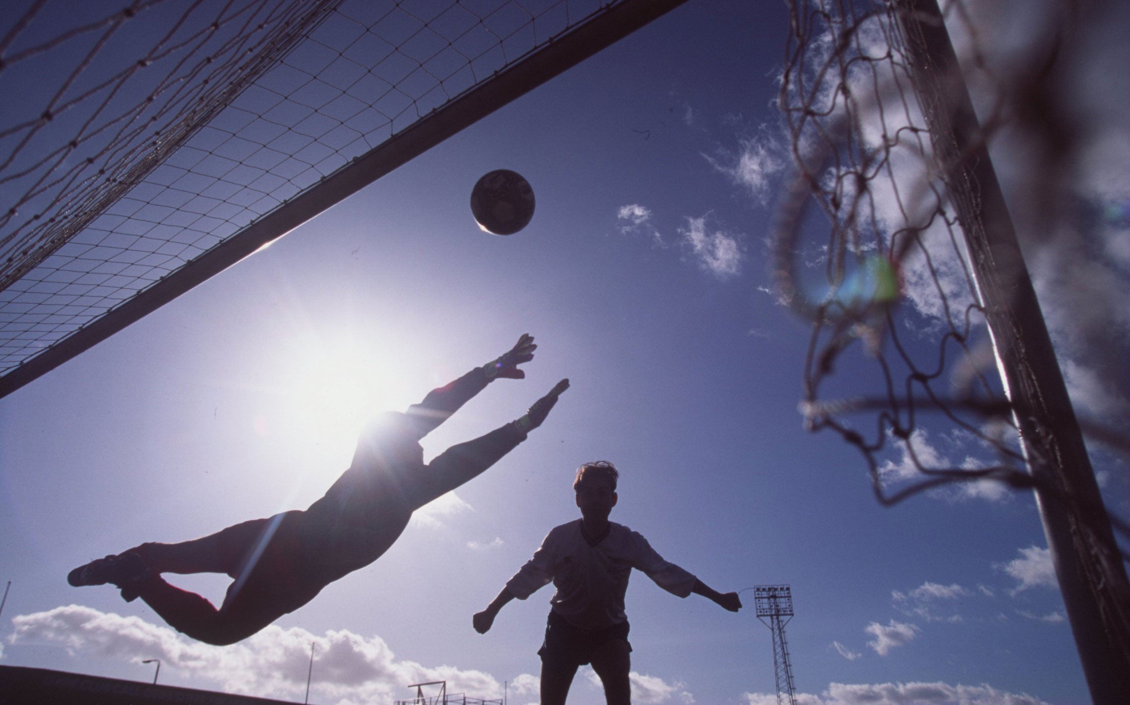 A footballer heads a ball into the net