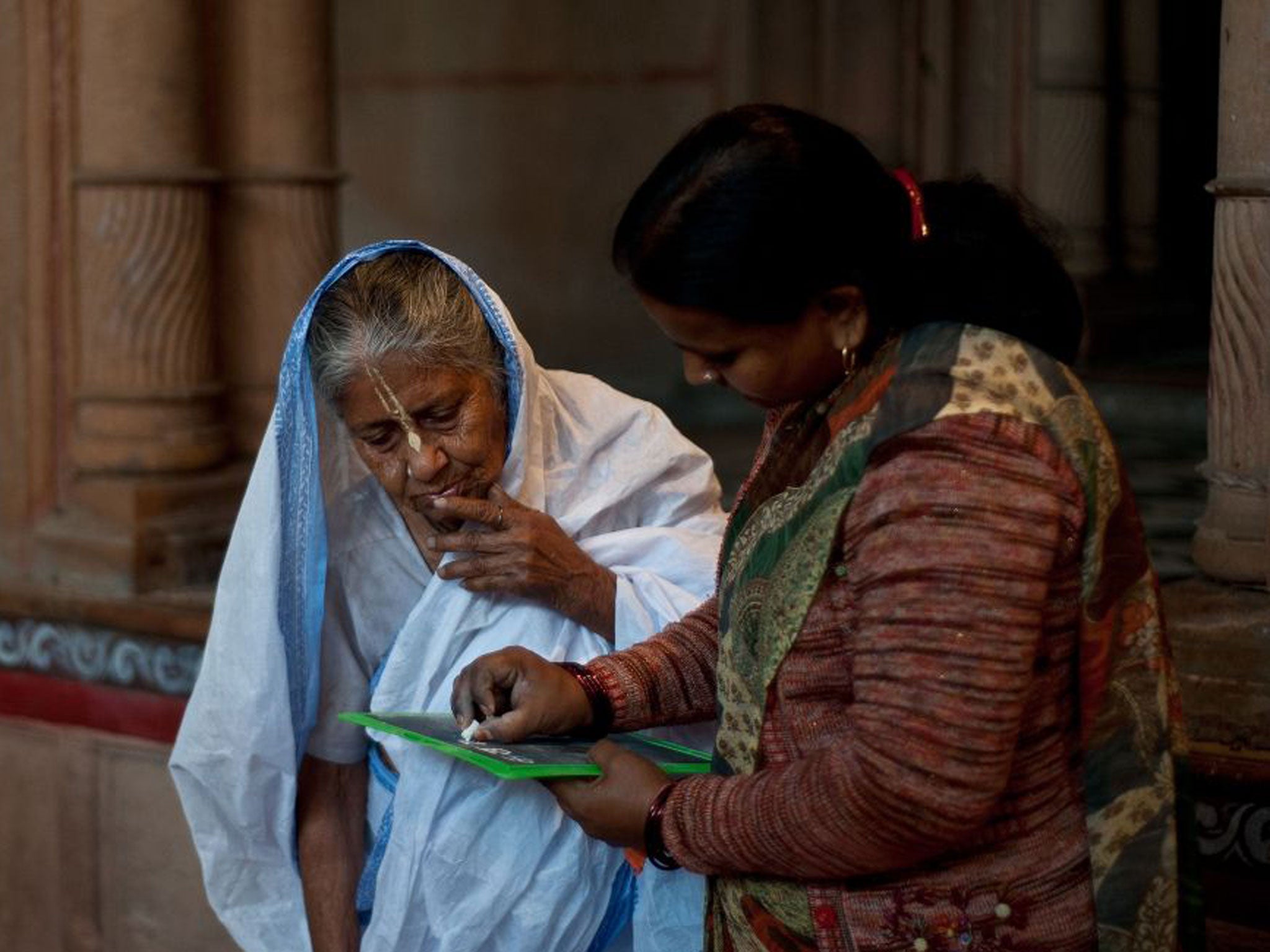 An elderlywidow being taught how to write in India, ranked 69th