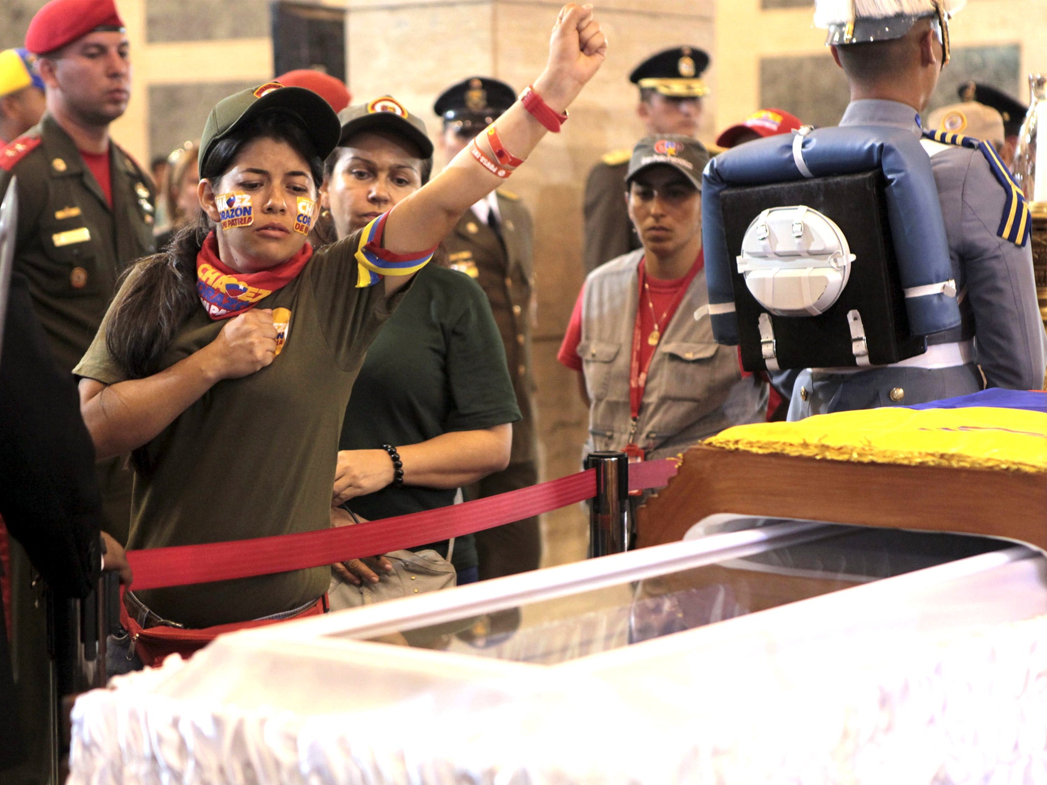 A supporter of the late Venezuelan President Hugo Chavez salutes as she views his coffin as his body lay in state in Caracas