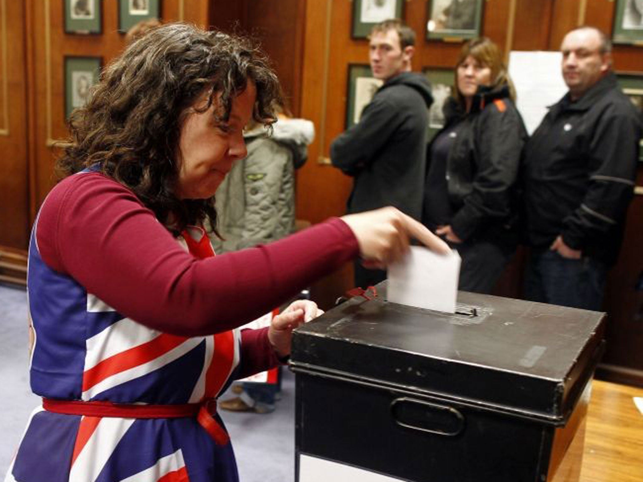 Falkland Islander Joan Turner, wearing a dress with the Union Jack colours, casts her vote at the Town Hall polling station in Stanley