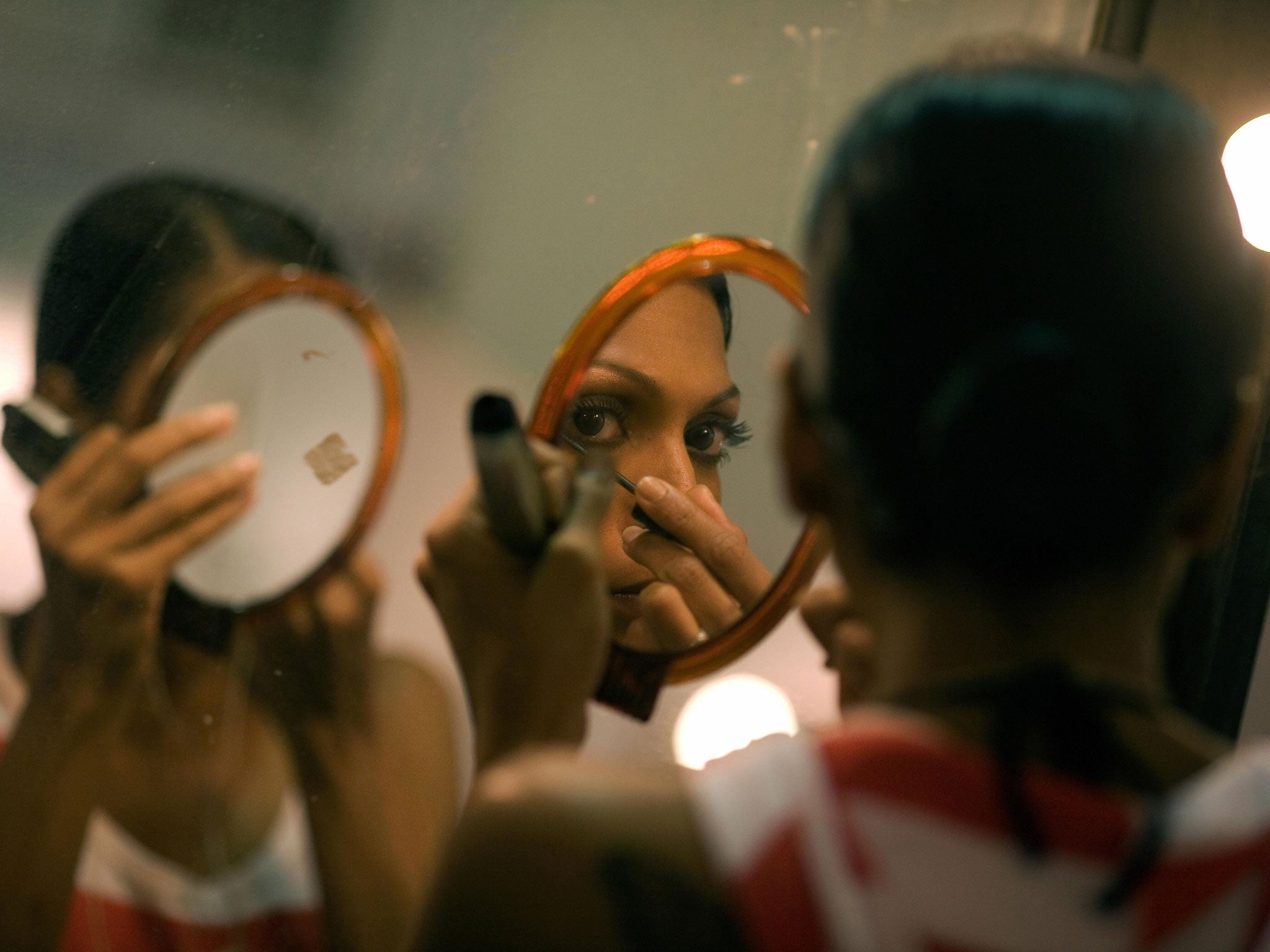 An Indian model is reflected in a mirror as she does her makeup before the Manav Gangwani show at the Wills India Fashion Week (WIFW) at Pragati Maidan in New Delhi on March 15, 2008.