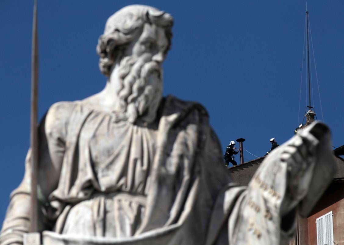 Firefighters place the chimney on the roof of the Sistine Chapel, where cardinals will gather to elect the new Pope