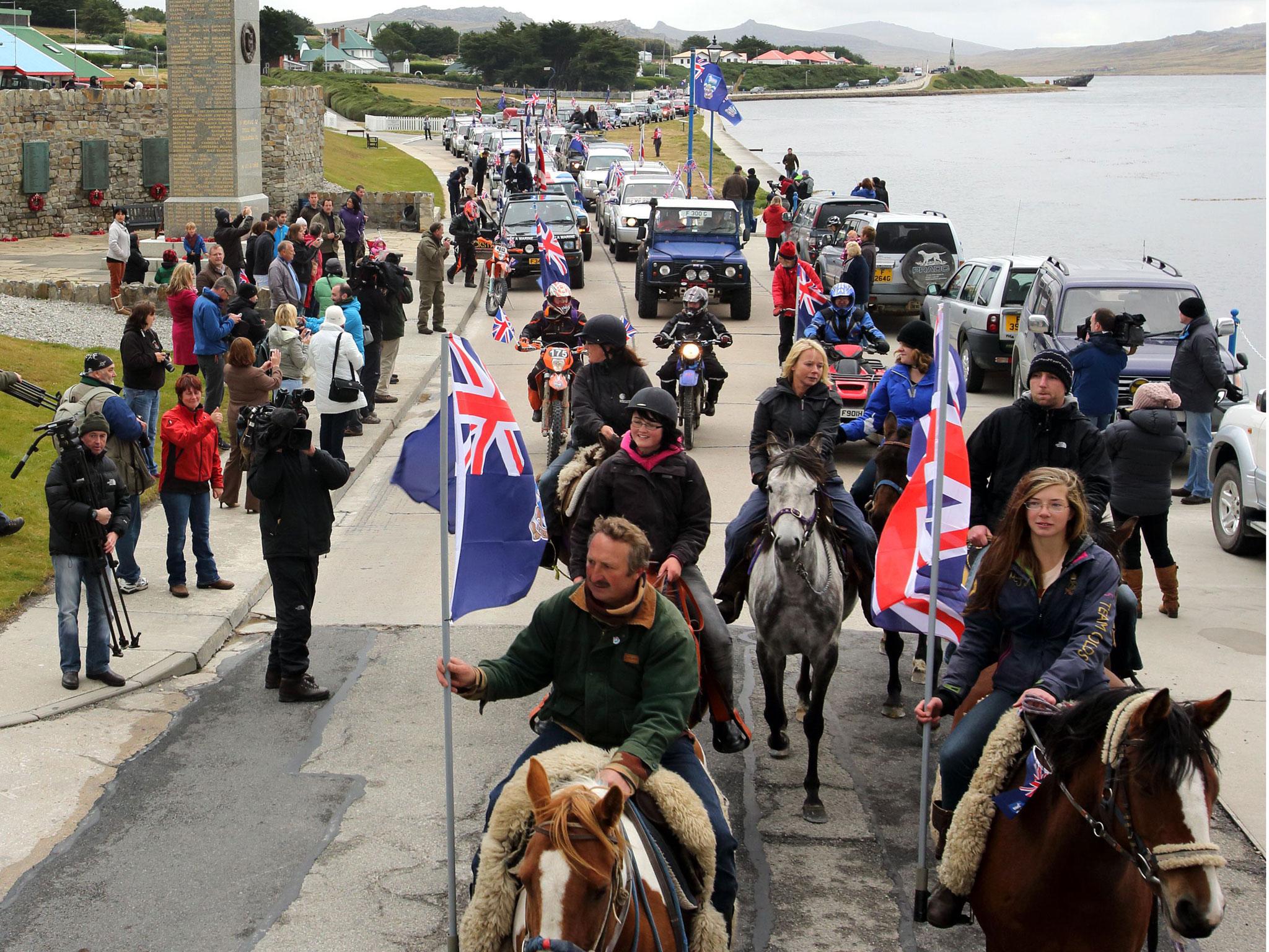 Islanders taking part in the "Proud to be British" parade pass by the 1982 memorial along Ross Road in Port Stanley