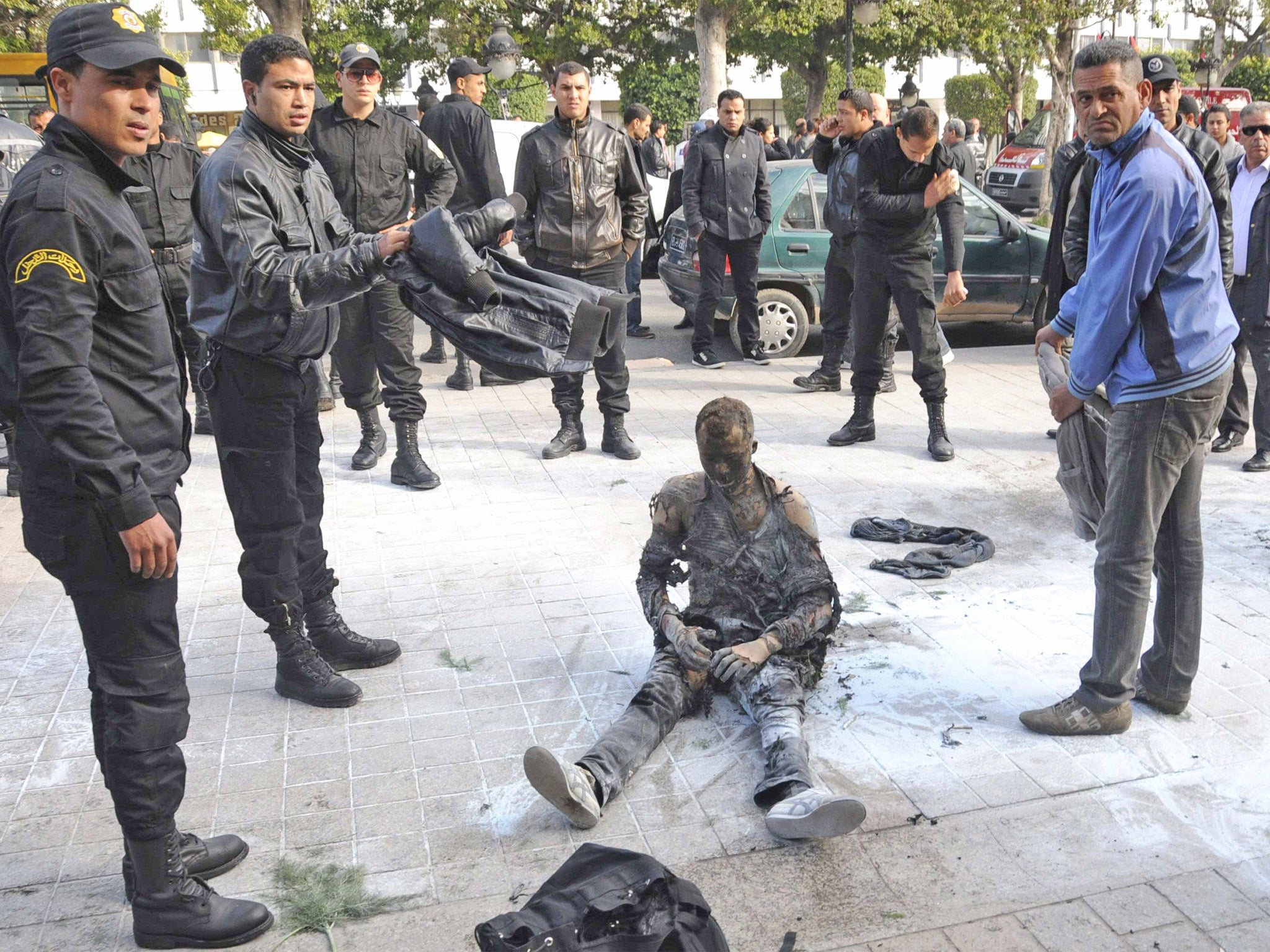 A young Tunisian man who set himself on fire is surrounded by security forces in Tunis