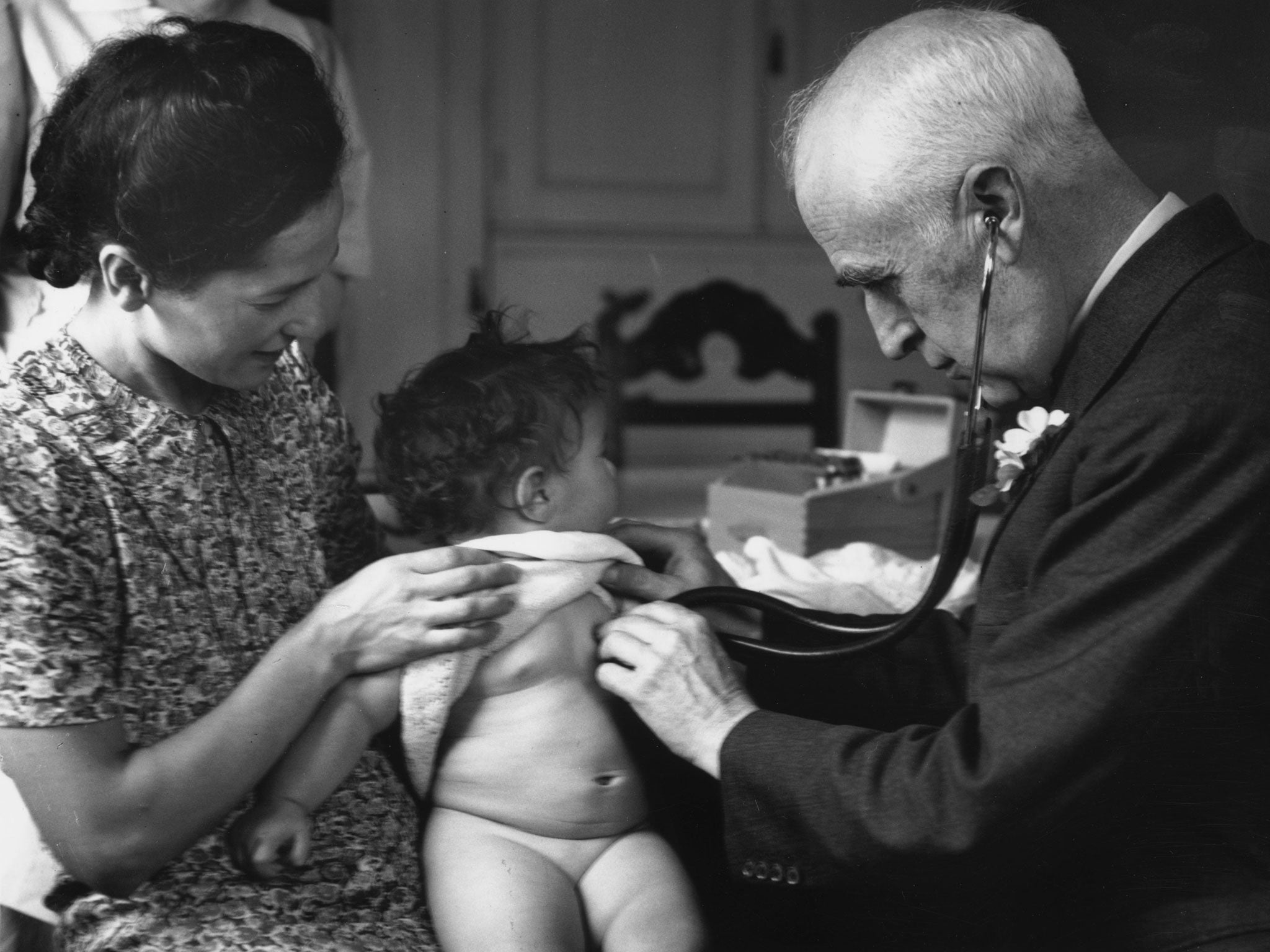 circa 1940: A doctor examining a young patient at a Welfare Centre clinic.
