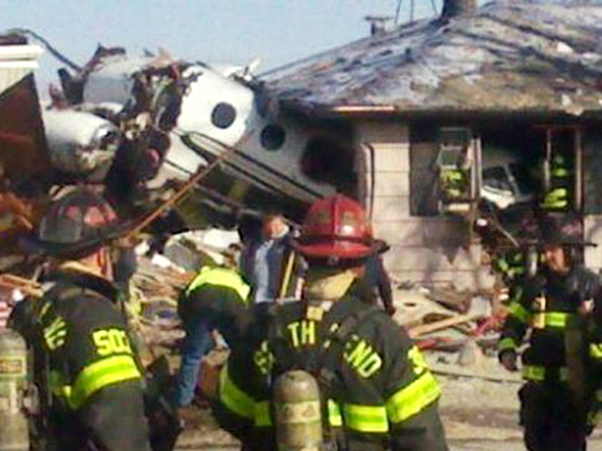 Firefighters and rescue workers look over the scene in South Bend, Indiana, after a small twin-jet aircraft crashed into houses near the airport