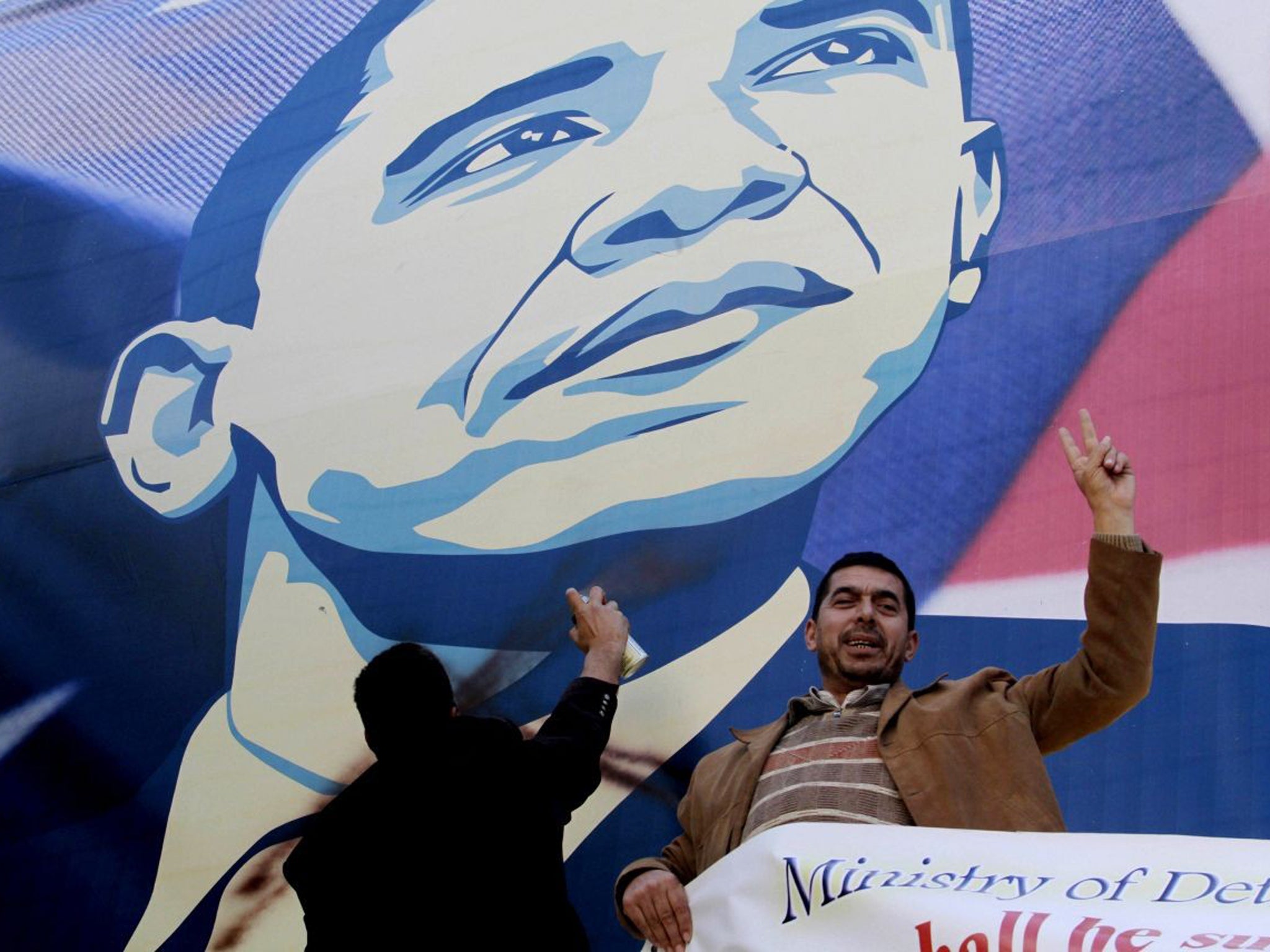 Palestinian activists vandalise a poster of US President Barack Obama in the West Bank city of Bethlehem
