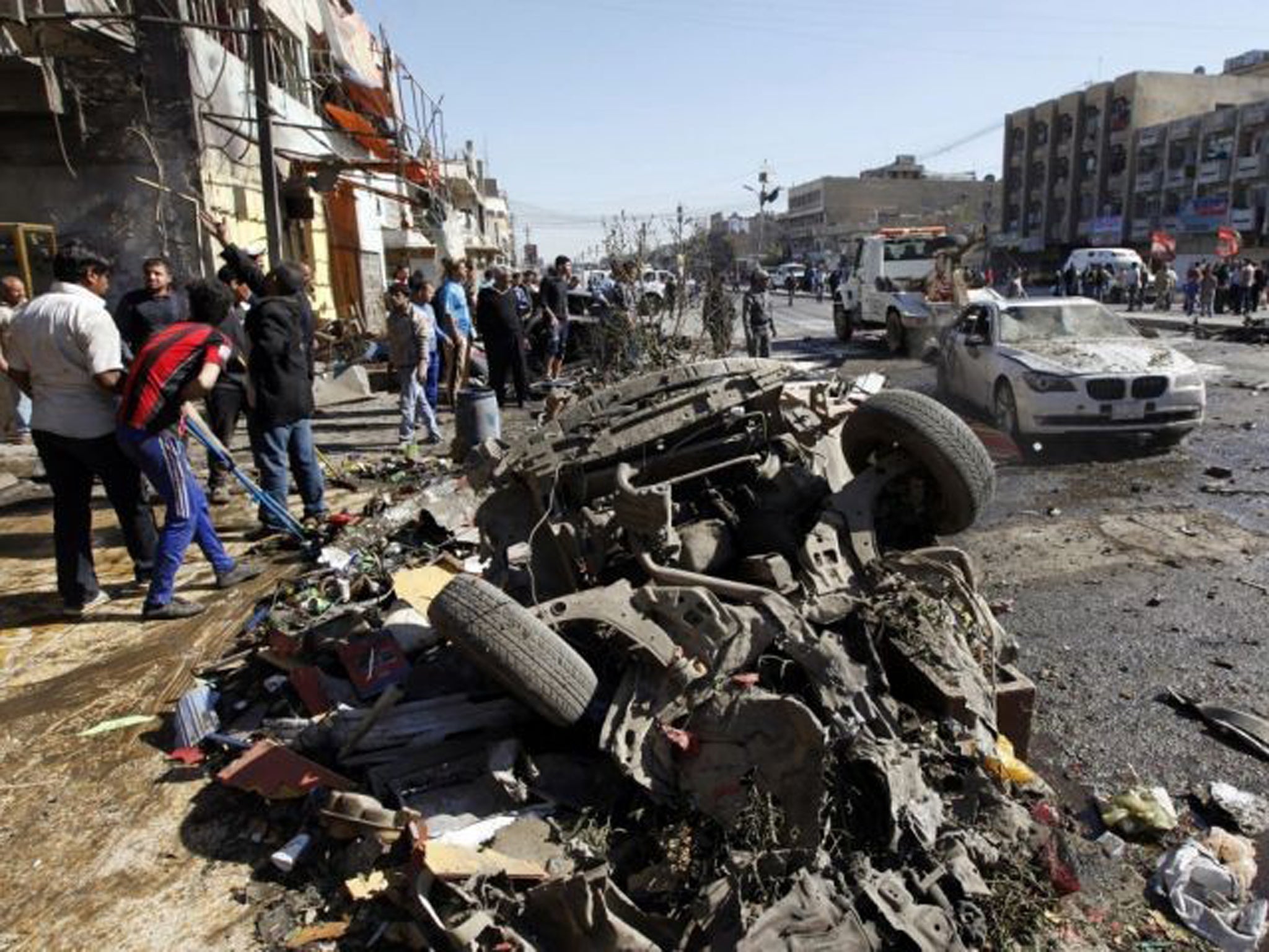 Residents gather at the site of a car bomb attack in the Al-Mashtal district in Baghdad