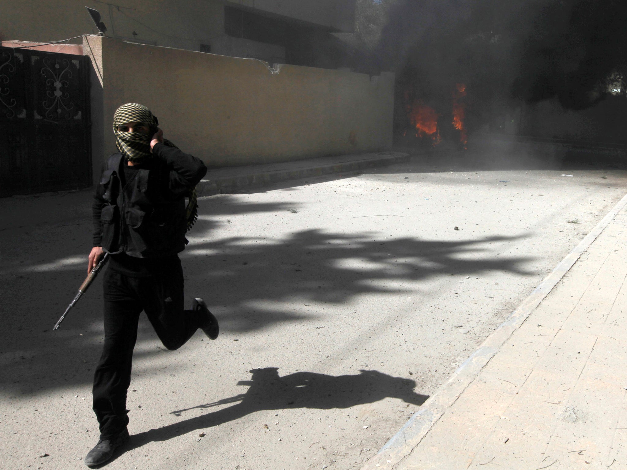 A fighter from Islamist Syrian rebel group Jabhat al-Nusra runs with his weapon as their base is shelled in Raqqa province, eastern Syria