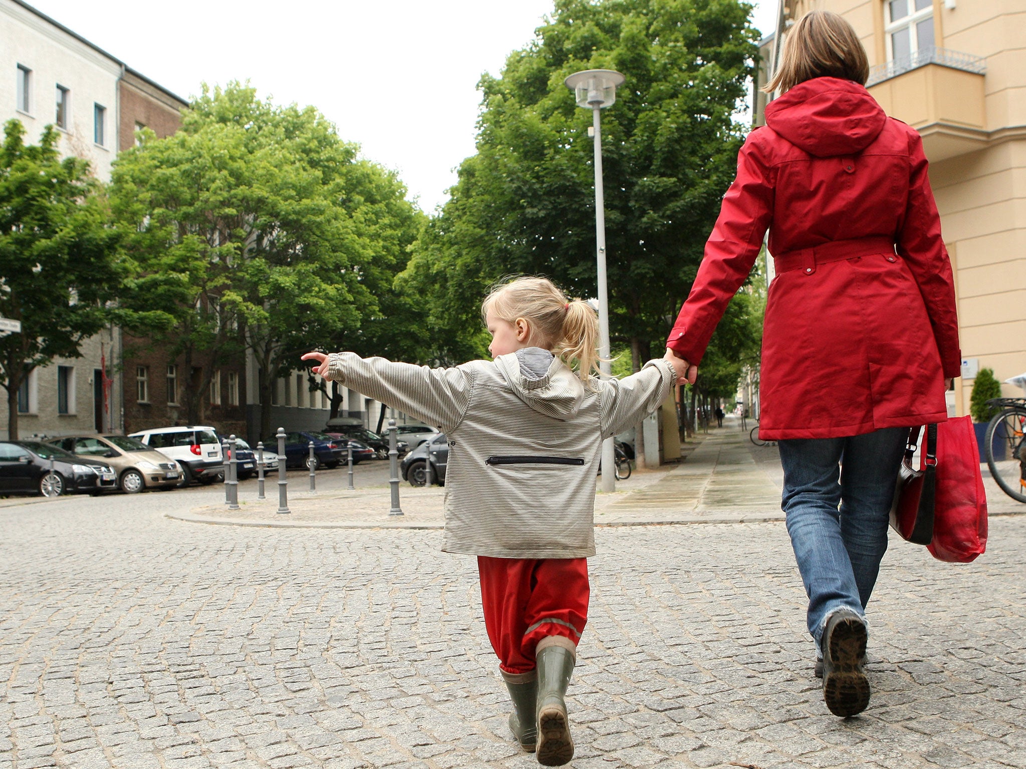 A three-year-old girl indicates to her mother that no traffic is coming as they cross the street on the way to a playground on June 6, 2012 in Berlin, Germany.