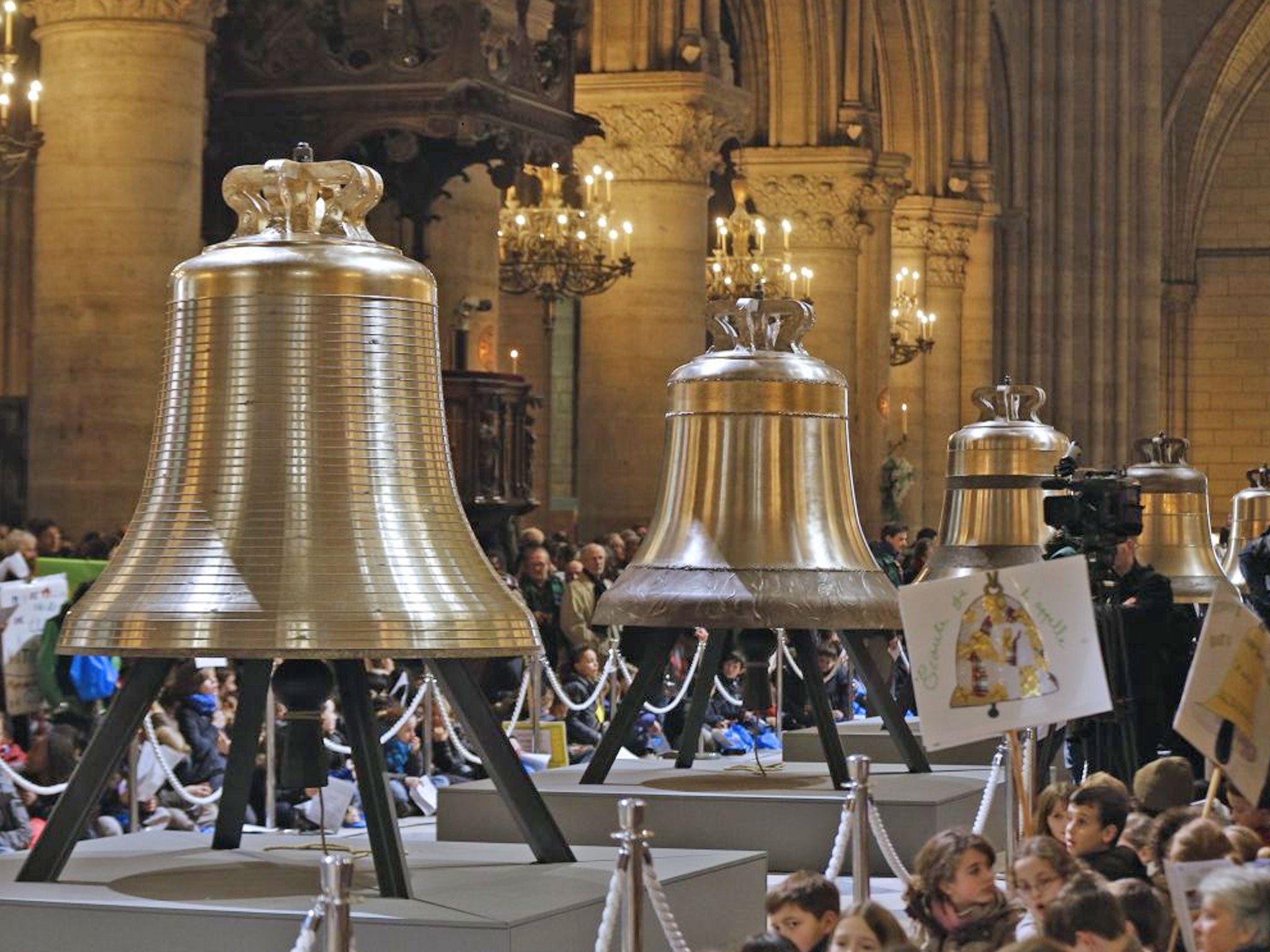 People gather around the new bells of Notre-Dame de Paris Cathedral during their blessing mass