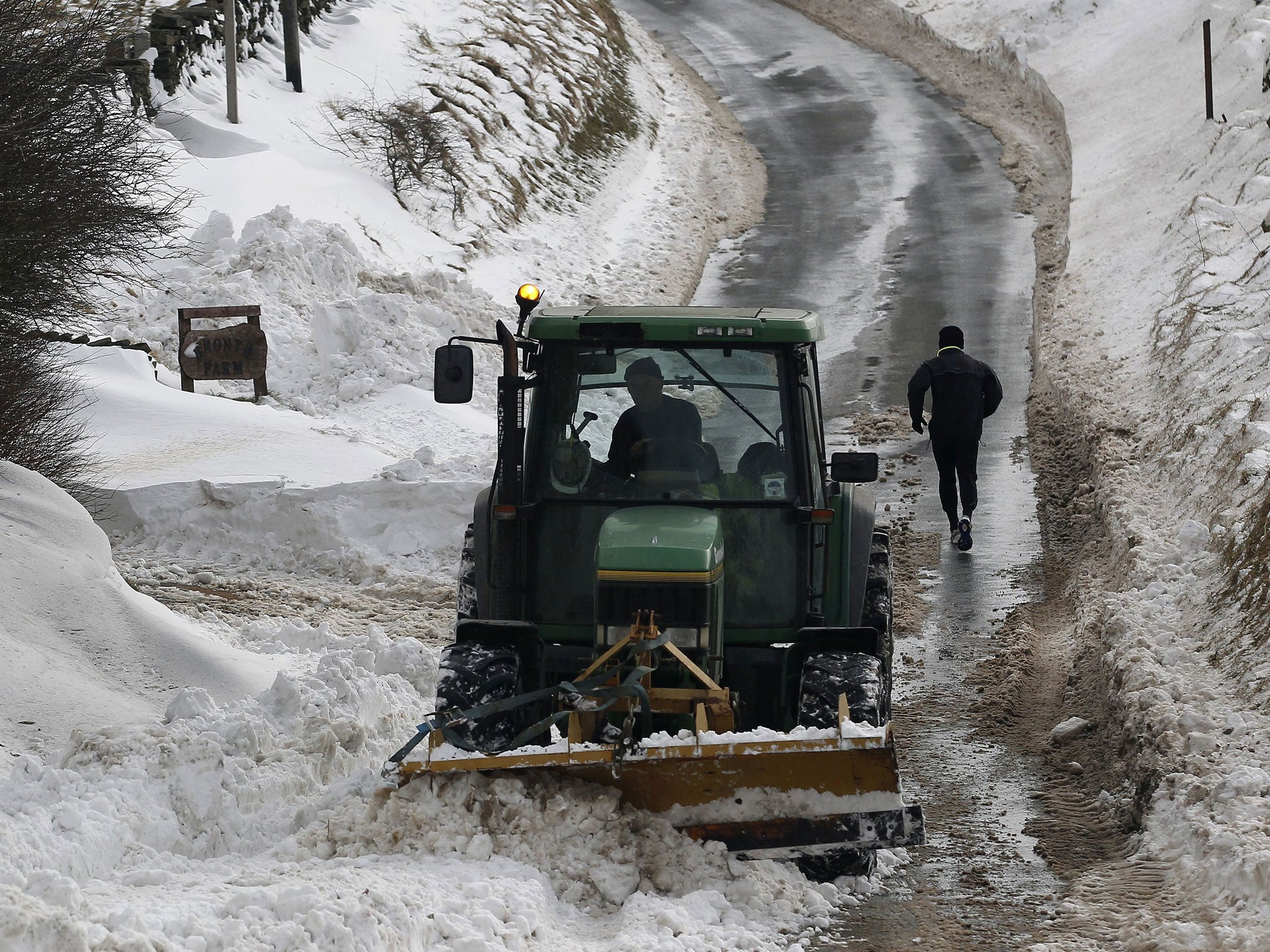 A runner makes his way up a cleared road flanked by deep snow in Burnley